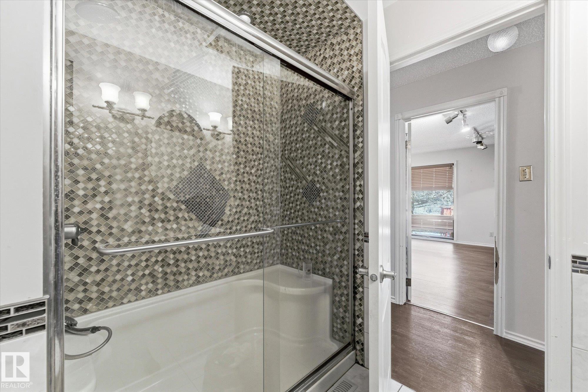 Tub-shower combination featuring sliding glass doors and mosaic tile surround - 25750 18 Street, Edmonton, AB - Indoor