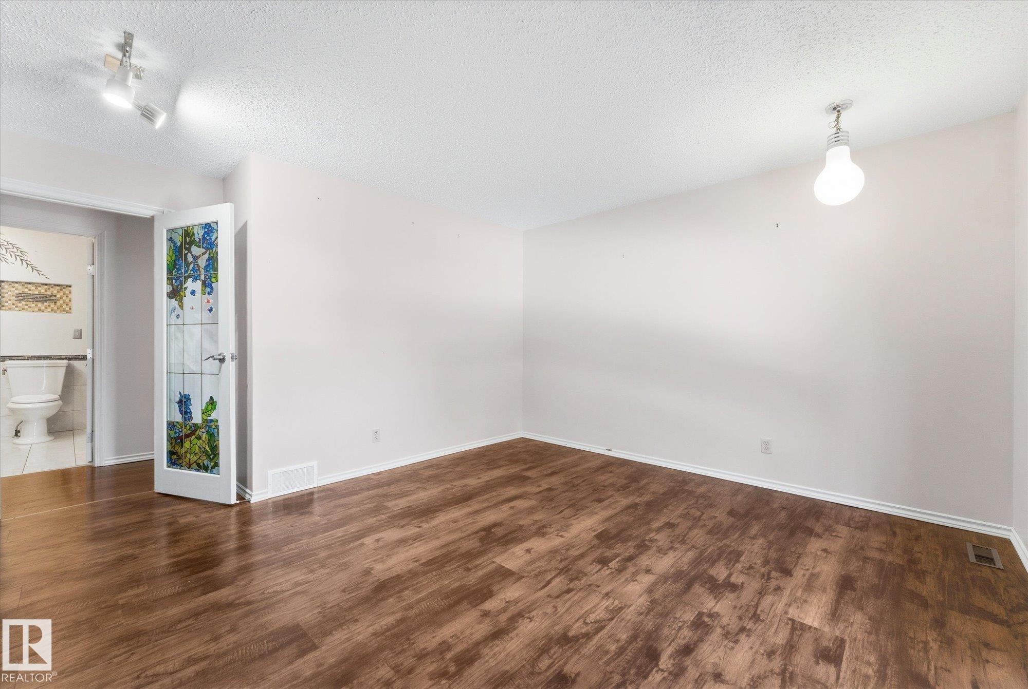 Spacious room featuring wood-finish flooring and white baseboards - 25750 18 Street, Edmonton, AB - Indoor Photo Showing Other Room