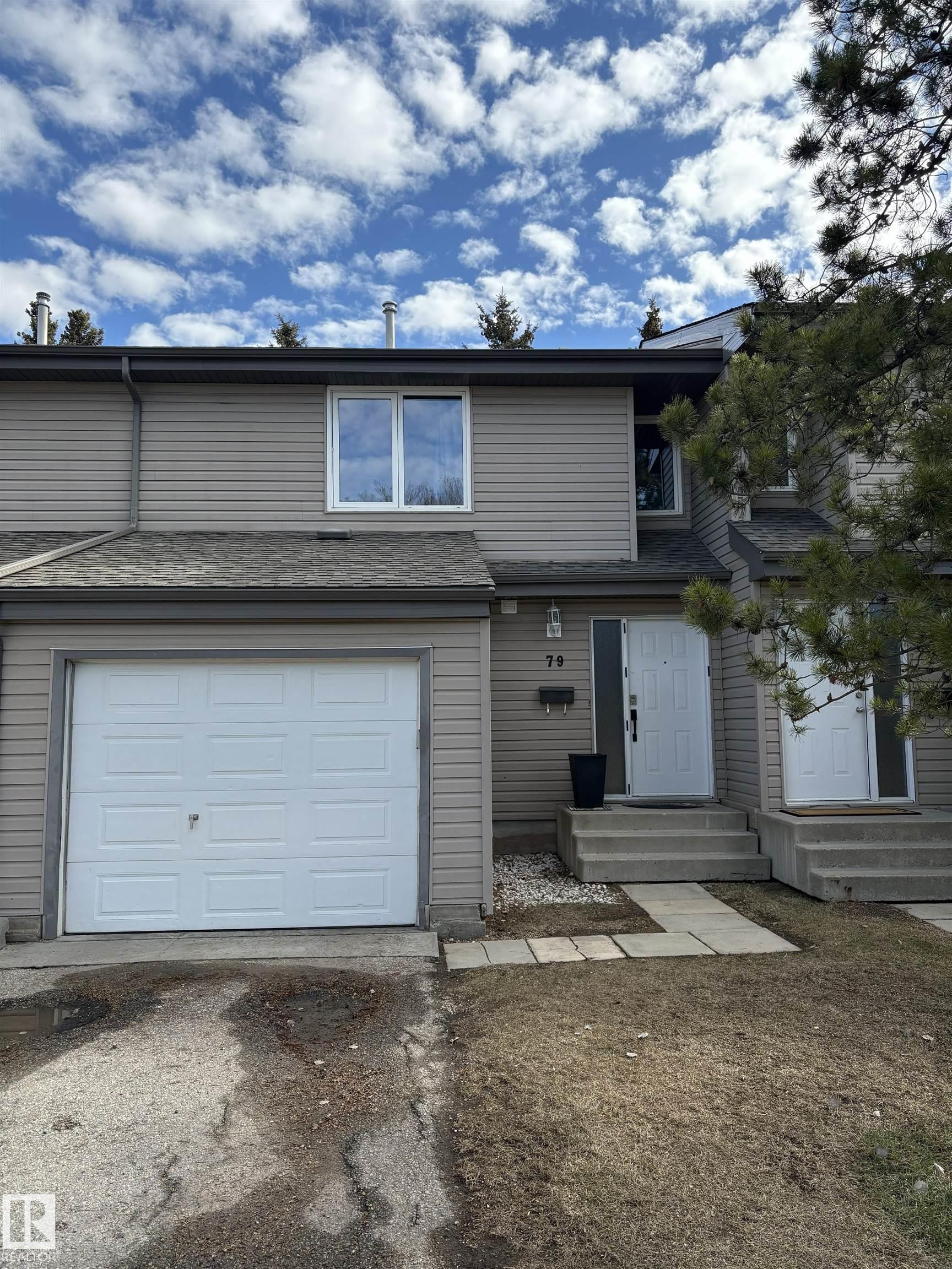 Contemporary two-story townhouse featuring neutral-toned siding and a white paneled garage door - 79 Akinsdale Gardens, St. Albert, AB - Outdoor