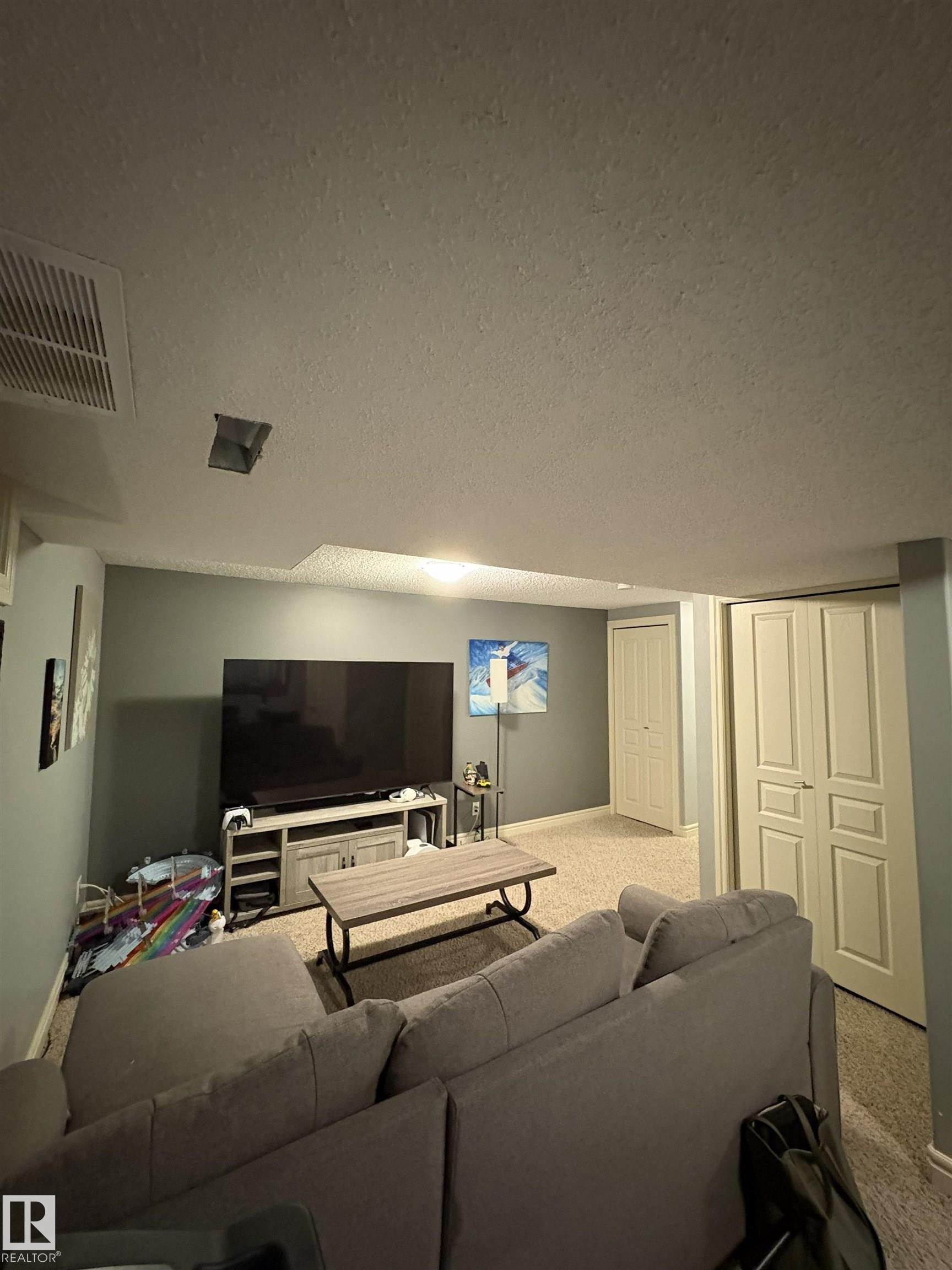 Carpeted room with light gray walls, featuring two paneled doors and recessed ceiling lighting - 79 Akinsdale Gardens, St. Albert, AB - Indoor