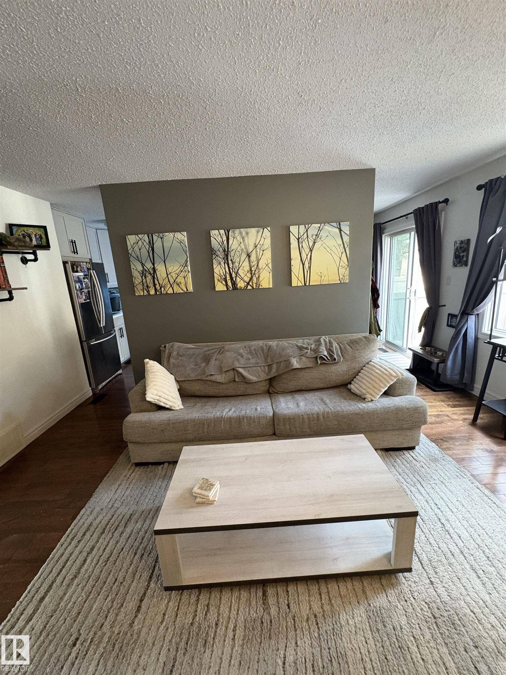 Living area featuring wood-finish flooring and a textured area rug - 79 Akinsdale Gardens, St. Albert, AB - Indoor Photo Showing Living Room