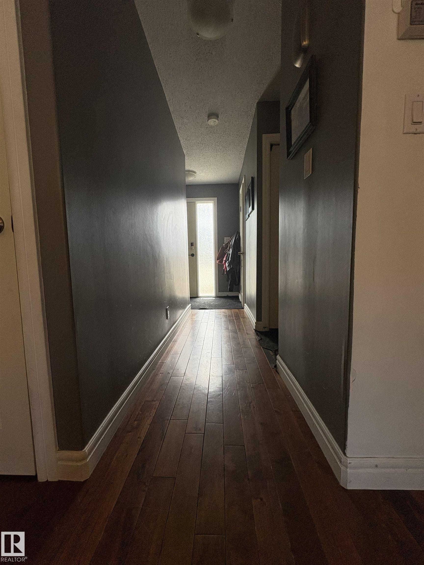 Hallway featuring wood-finish flooring, dark gray wall paint, and white trim - 79 Akinsdale Gardens, St. Albert, AB - Indoor Photo Showing Other Room