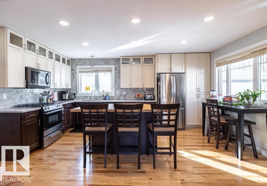 The kitchen features hardwood floors, a central island with seating, stainless steel appliances, and ample cabinetry - 71 Labelle Crescent, St. Albert, AB - Indoor