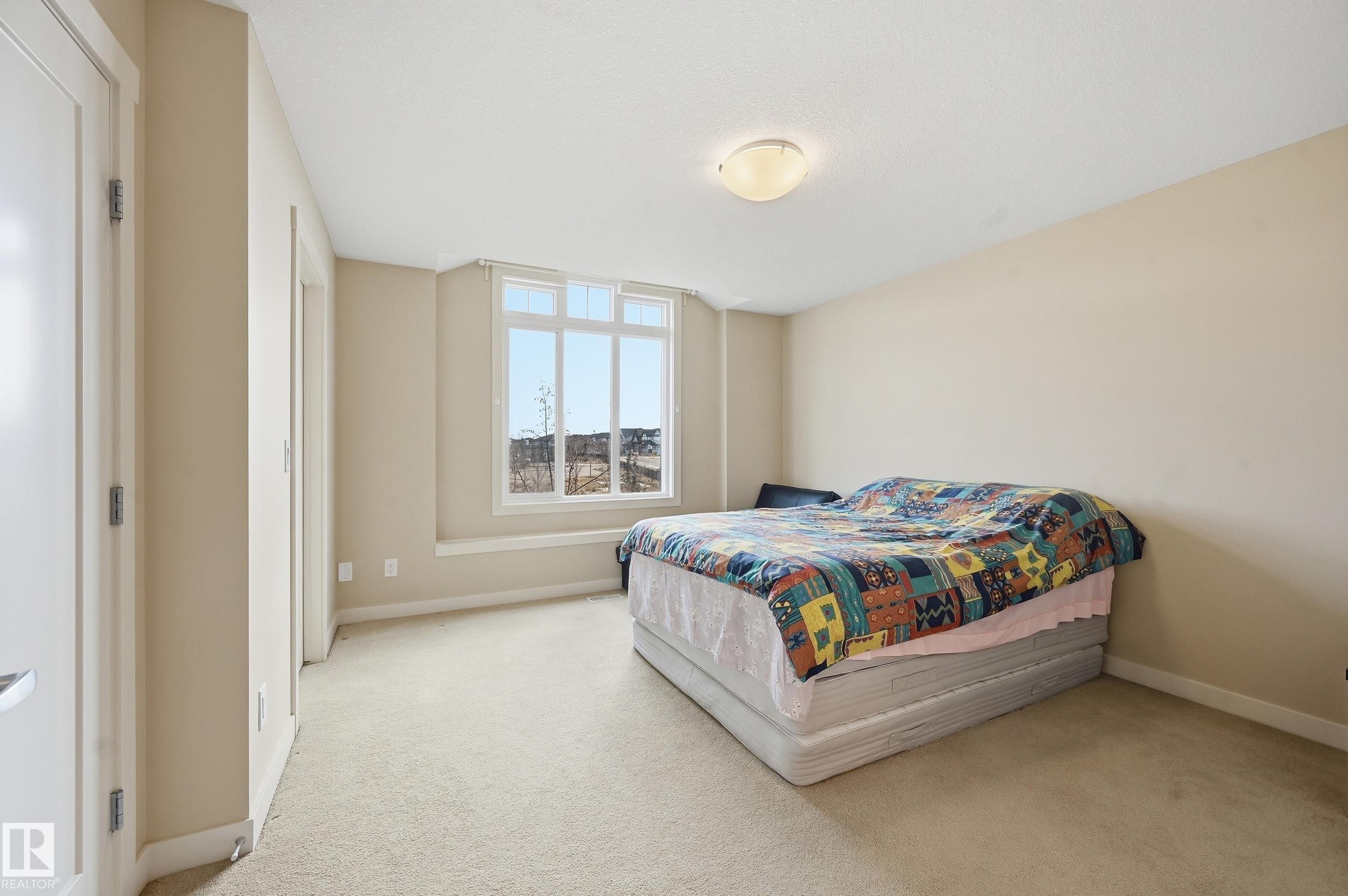 This room features a window with a wide sill, light-colored carpeting, and neutral-toned walls - 701 Allard Boulevard, Edmonton, AB - Indoor Photo Showing Bedroom
