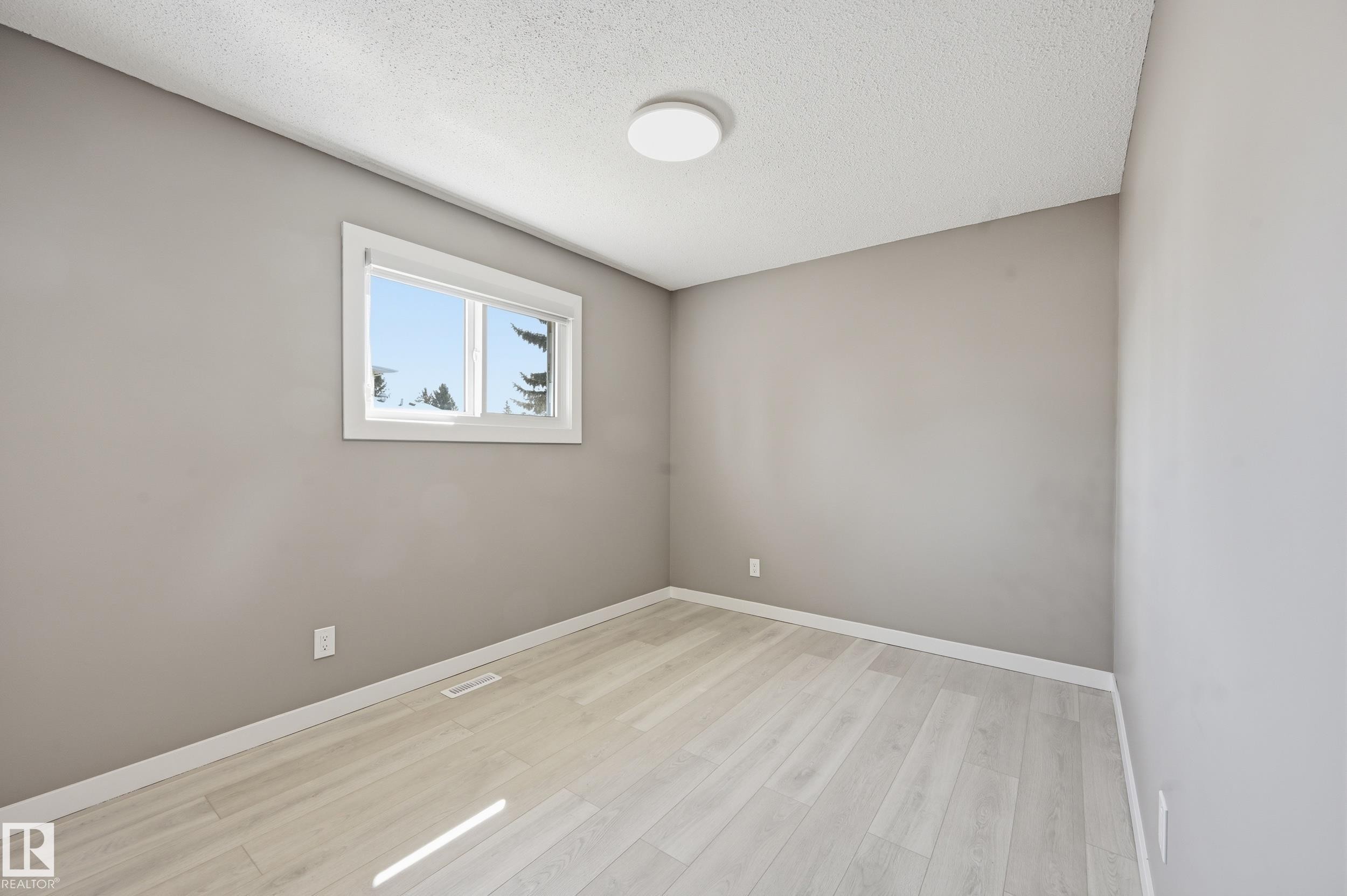This room features light-colored flooring, a window with white trim, and a ceiling light fixture - 6907 19 Avenue, Edmonton, AB - Indoor Photo Showing Other Room
