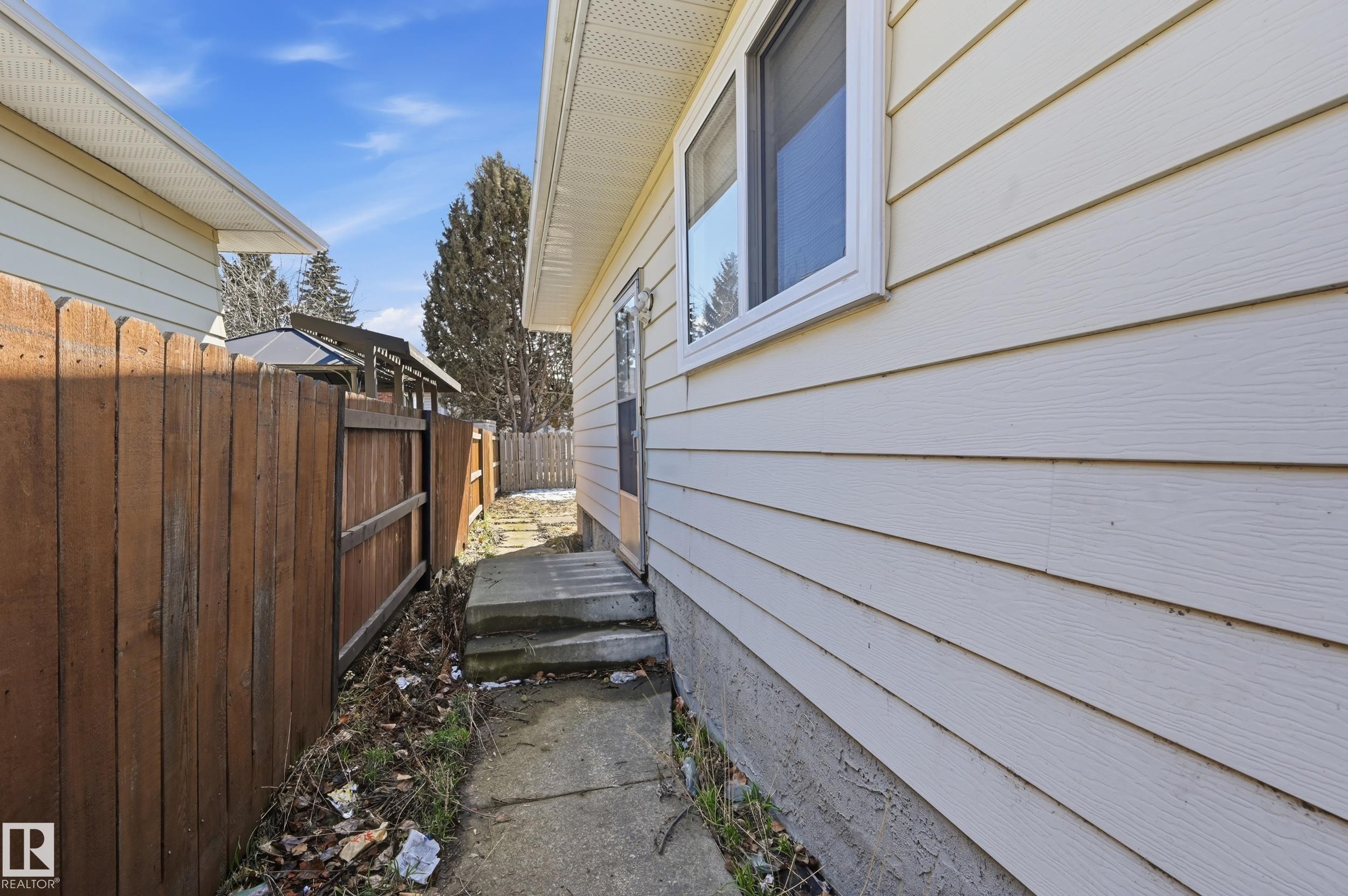 The property features light-colored horizontal siding and a window with white trim - 6907 19 Avenue, Edmonton, AB - Outdoor With Exterior