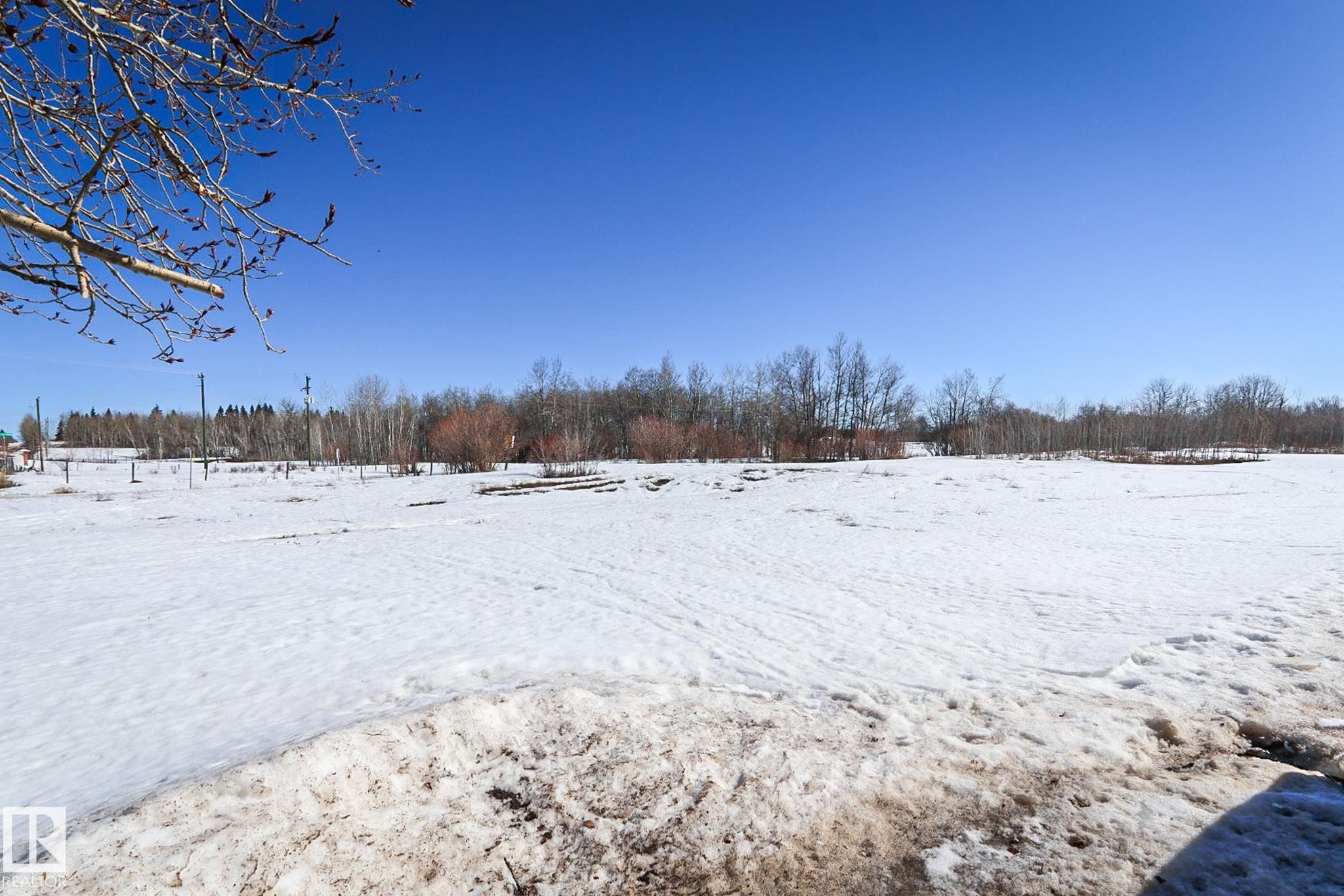 Expansive open land with a clear blue sky, bordered by natural tree lines - Sw-34-59-12-4, Spedden, AB