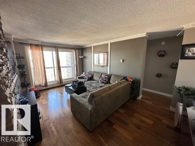 Spacious living area featuring wood-finish flooring, a stacked stone accent wall, and crown molding - 86 13435 97 Street, Edmonton, AB - Indoor Photo Showing Living Room