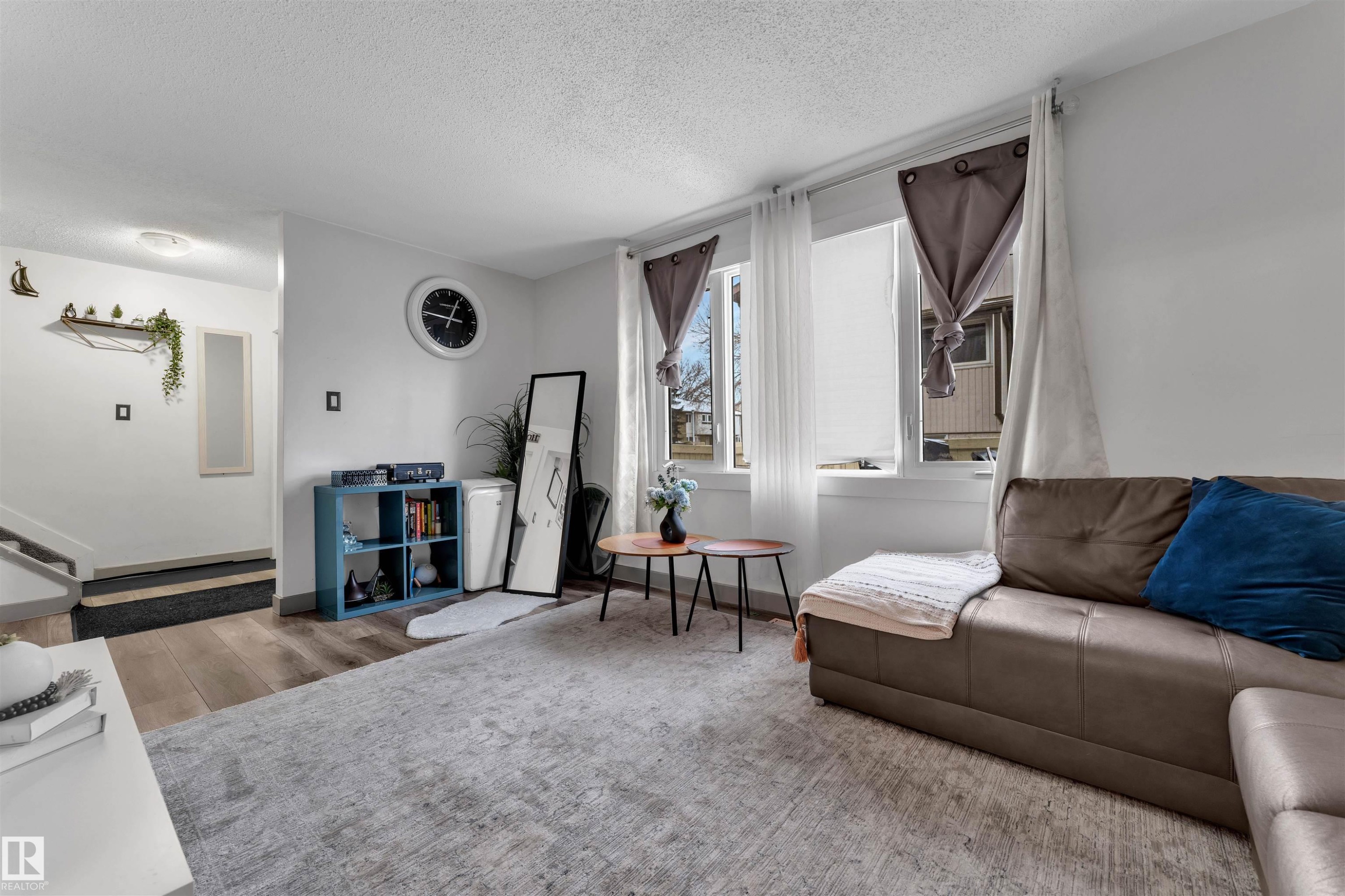 Living area featuring light wood-finish flooring, white walls, and bright windows with white blinds - 7 14115 82 Street, Edmonton, AB - Indoor Photo Showing Living Room