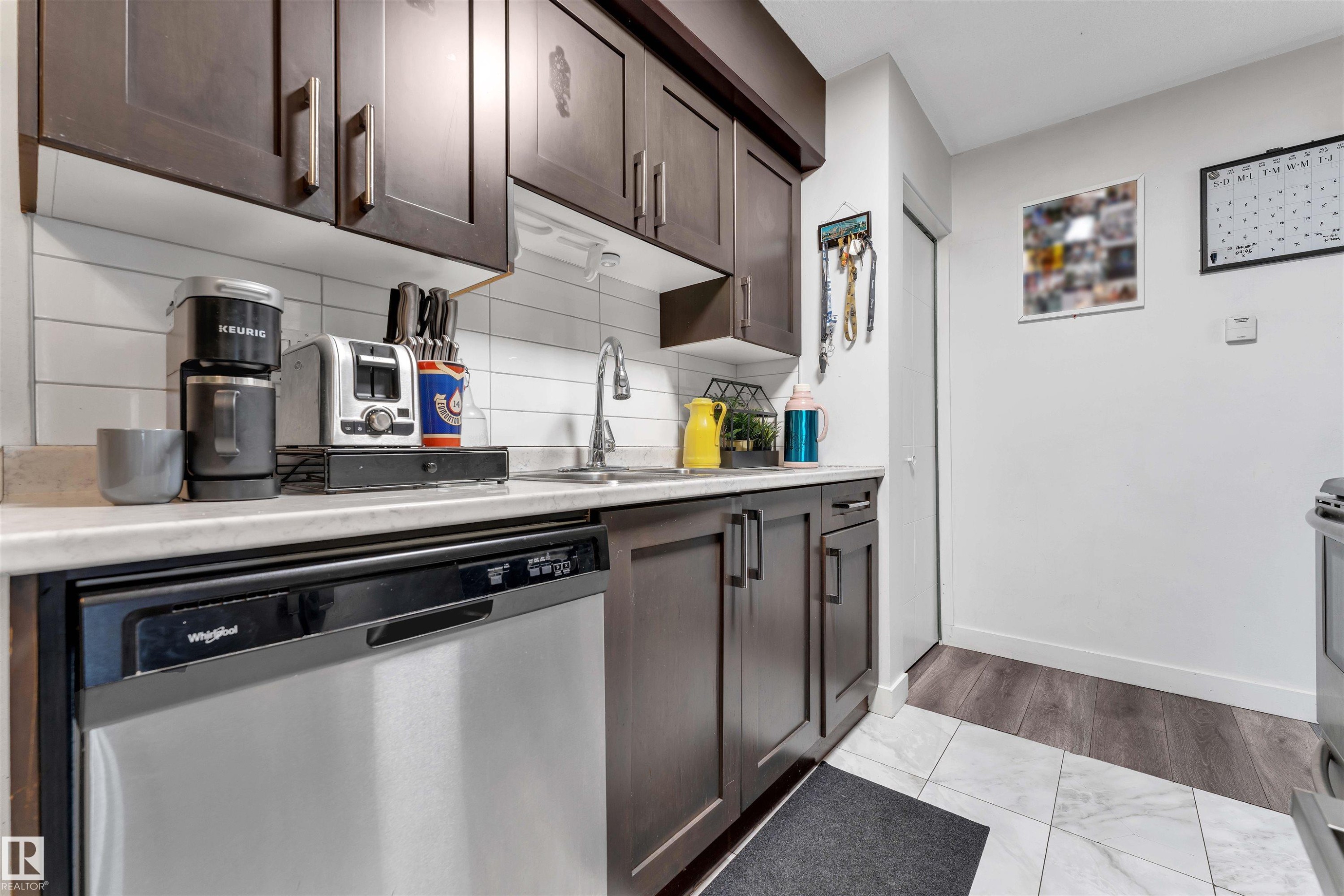 Kitchen with dark wood-finish cabinetry, light-toned countertops, and a white subway tile backsplash - 7 14115 82 Street, Edmonton, AB - Indoor Photo Showing Kitchen With Double Sink