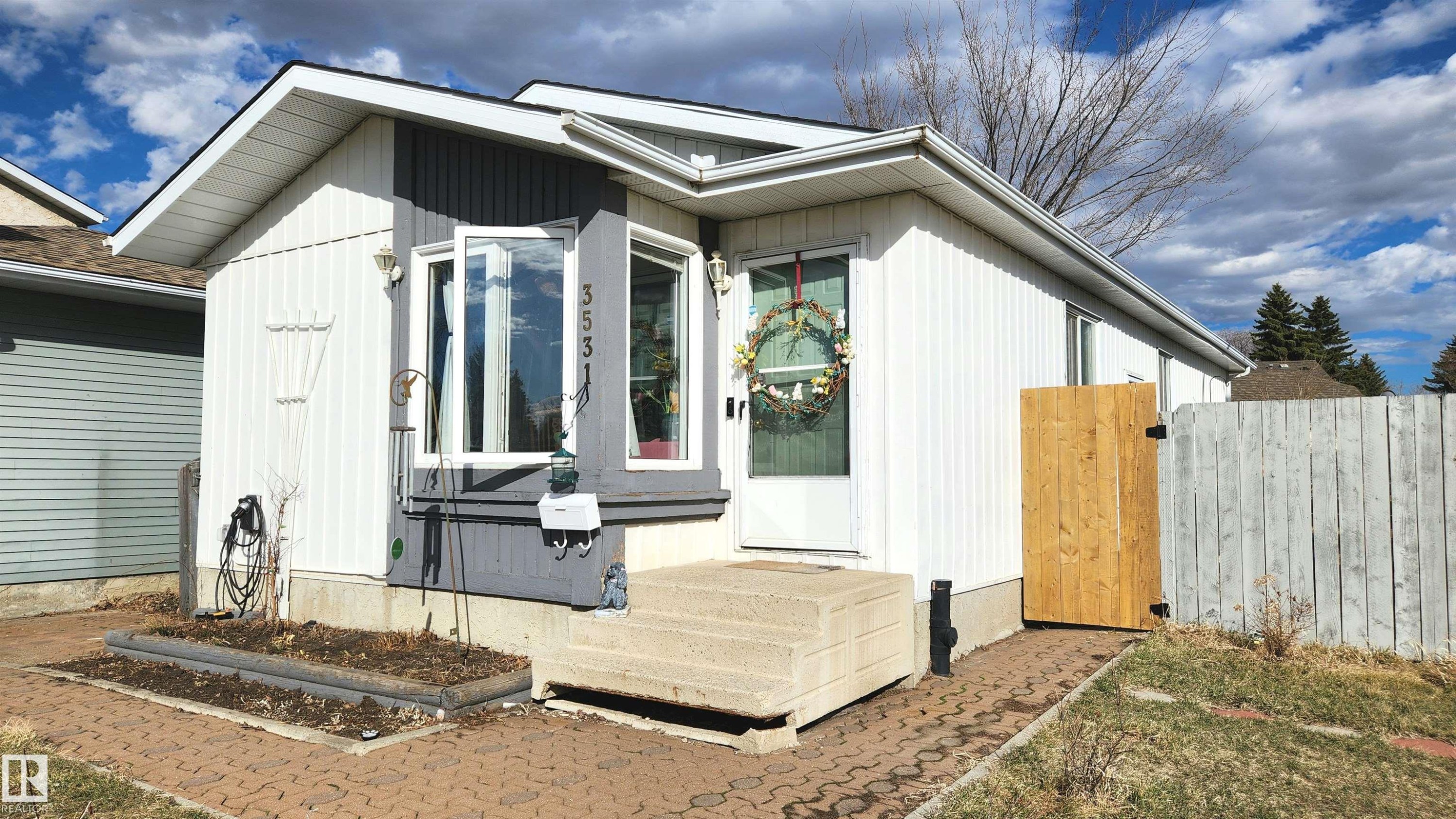 Exterior facade featuring white siding with gray accents, a bay window, and a concrete entry path - 3531 46 Street, Edmonton, AB - Outdoor