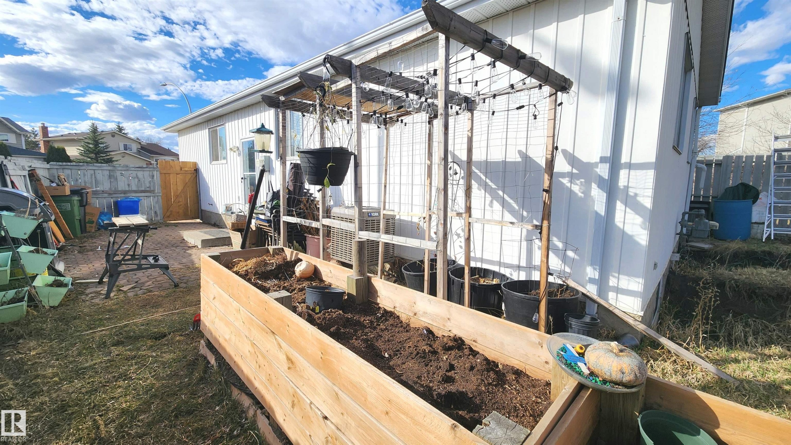 Expansive raised garden bed with a wooden trellis structure and string lighting - 3531 46 Street, Edmonton, AB - Outdoor