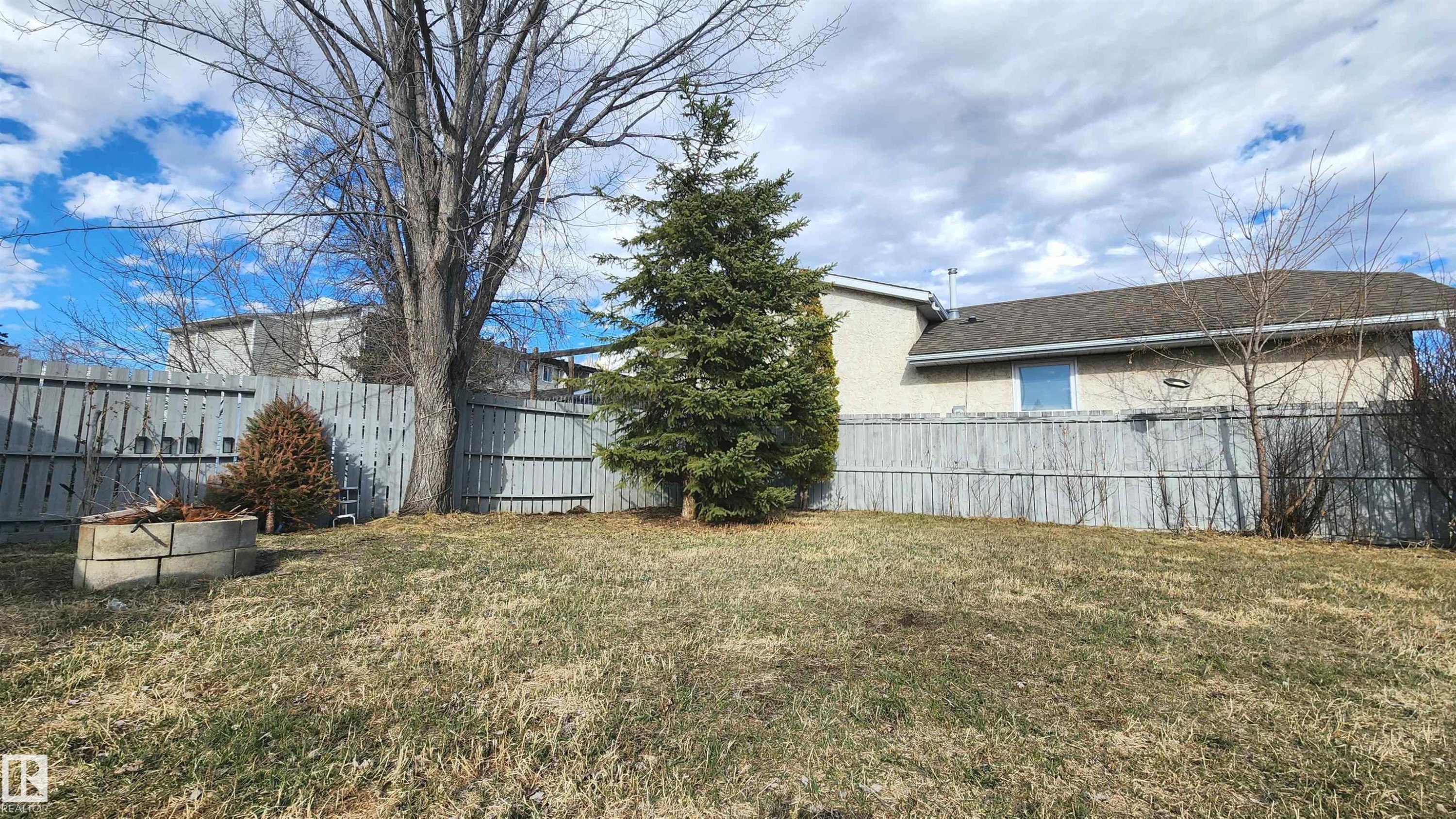 Expansive backyard featuring a full privacy fence, mature trees, and a concrete fire pit - 3531 46 Street, Edmonton, AB - Outdoor