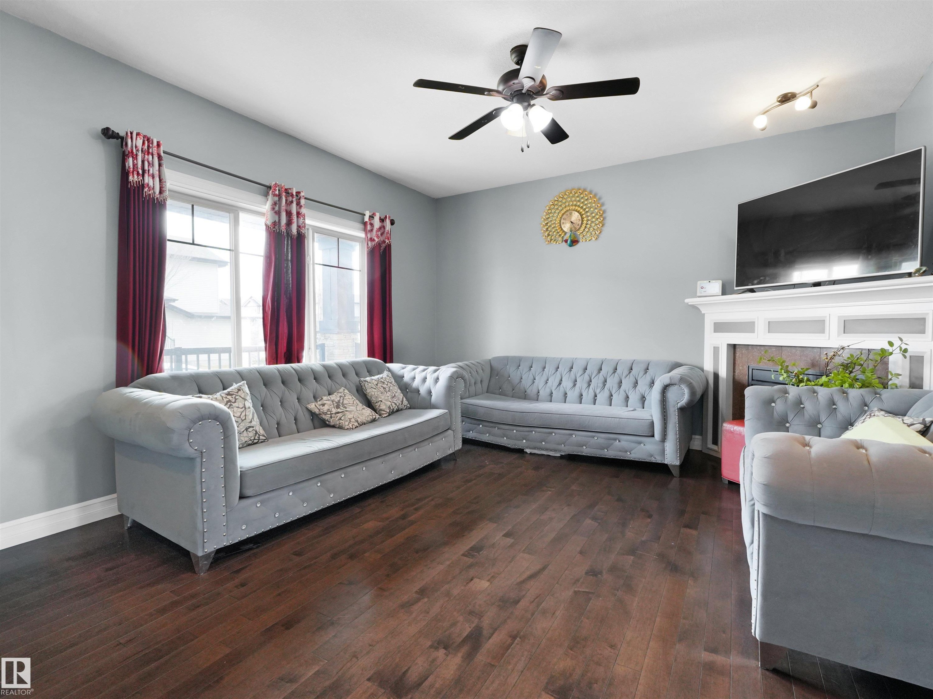 Spacious living area featuring wood-finish flooring, a ceiling fan with integrated lighting, and a white mantelpiece - 5192 1B Avenue Sw, Edmonton, AB - Indoor Photo Showing Living Room