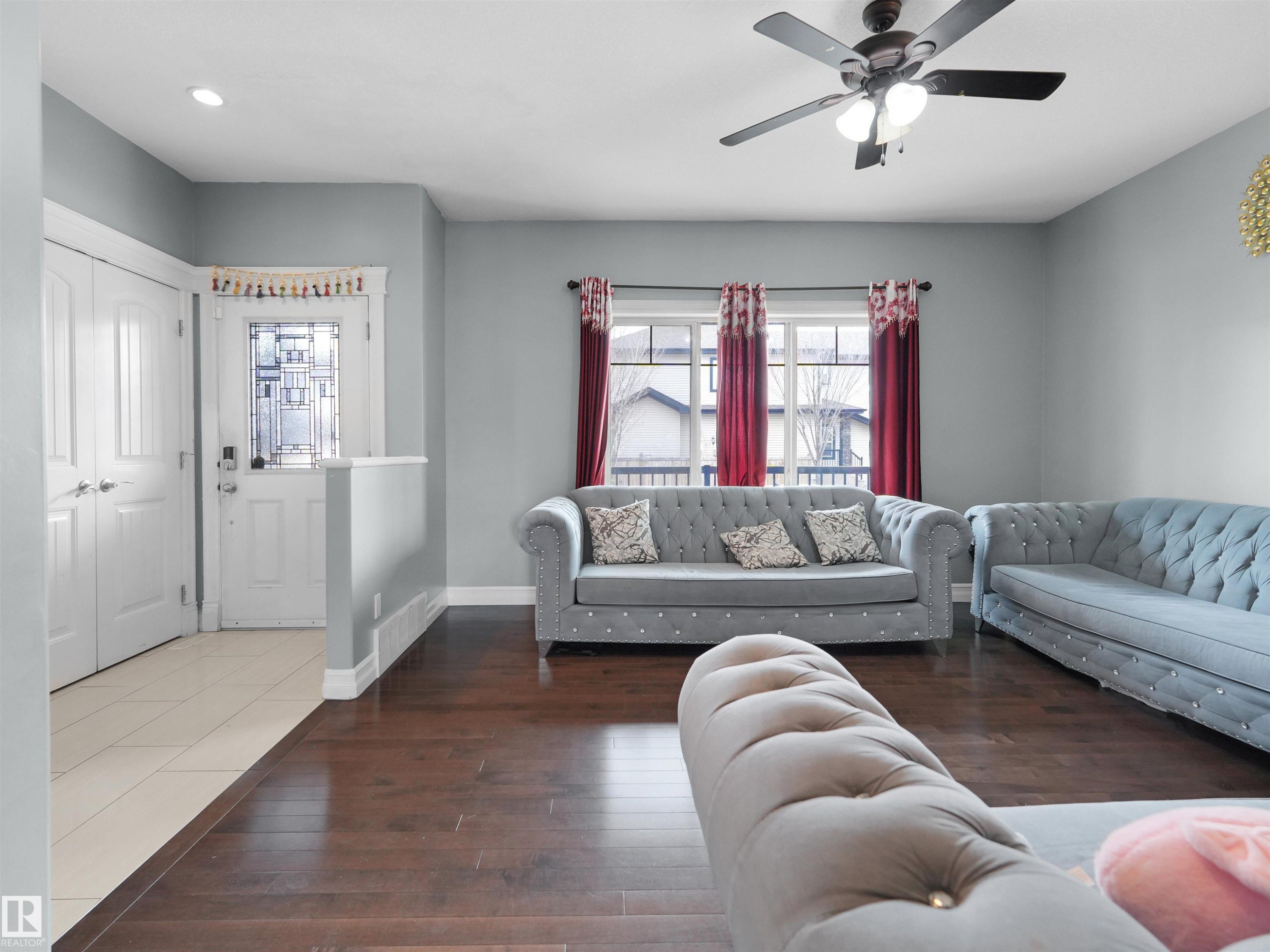 Living area featuring dark wood-finish flooring, light grey walls, and a ceiling fan with integrated lighting - 5192 1B Avenue Sw, Edmonton, AB - Indoor Photo Showing Living Room