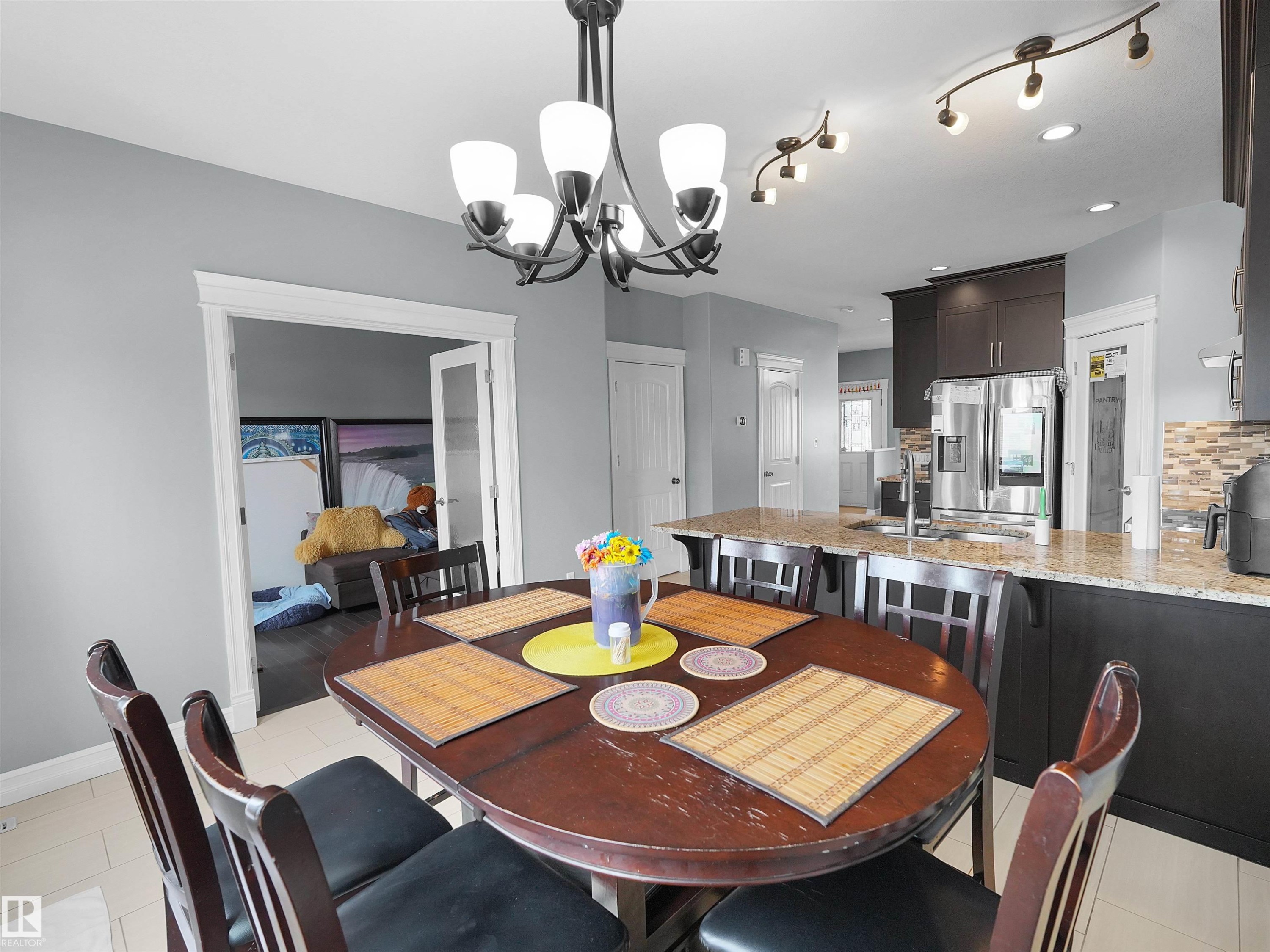 Dining area featuring a dark wood dining table with seating, chandelier lighting, and tile flooring - 5192 1B Avenue Sw, Edmonton, AB - Indoor Photo Showing Dining Room