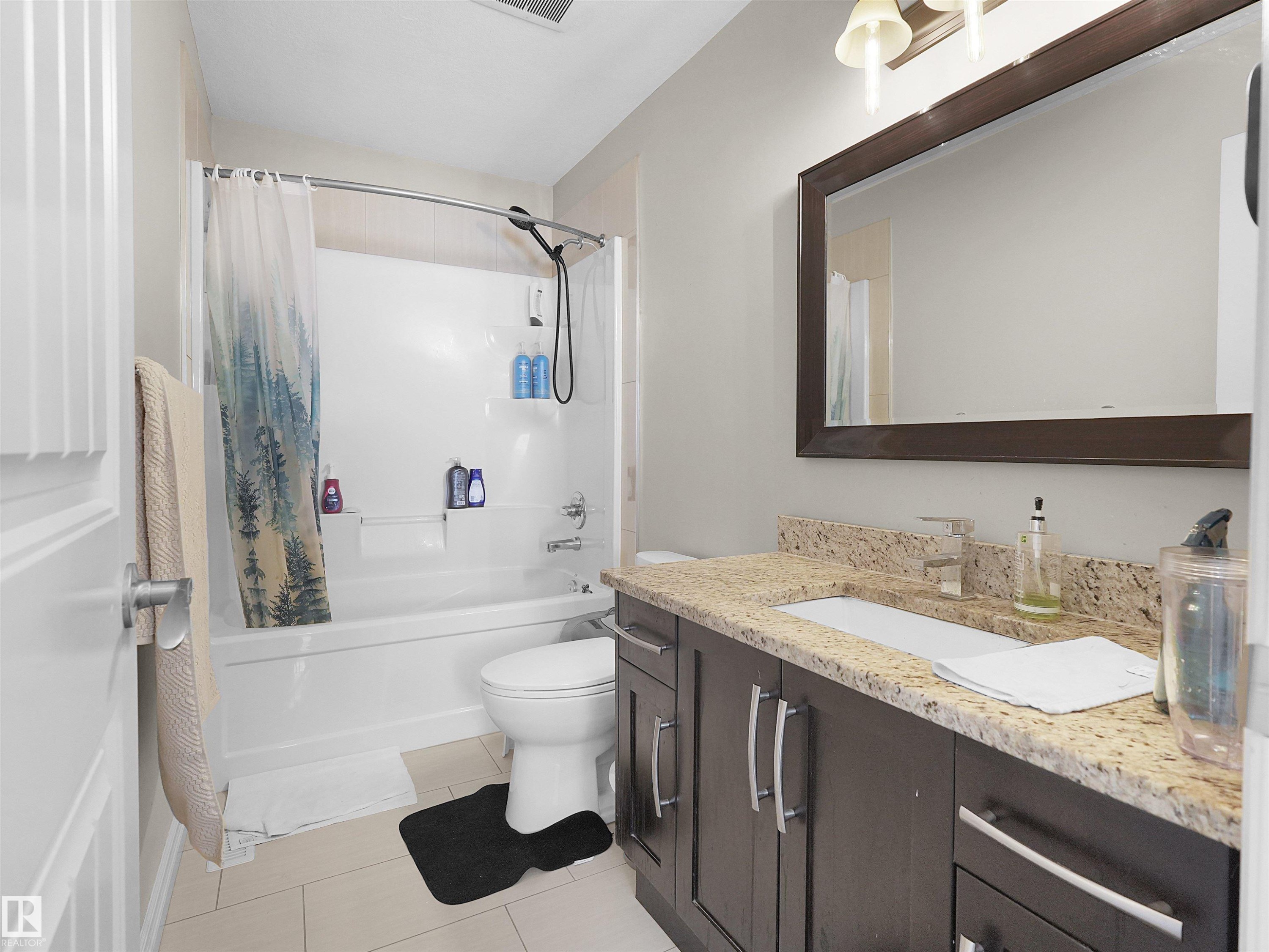 Bathroom featuring a dark wood-finish vanity with ample storage, a granite-style countertop, and an undermount sink - 5192 1B Avenue Sw, Edmonton, AB - Indoor Photo Showing Bathroom
