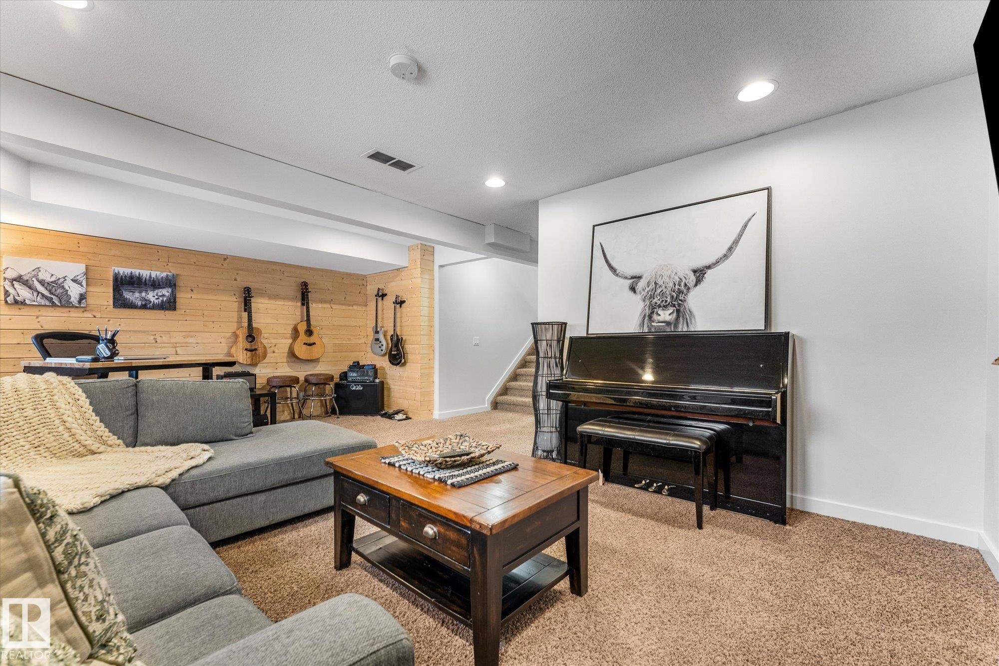 Living area featuring carpeted flooring, white walls, and a wood-paneled accent wall - 3908 44 Avenue, Stony Plain, AB - Indoor Photo Showing Other Room