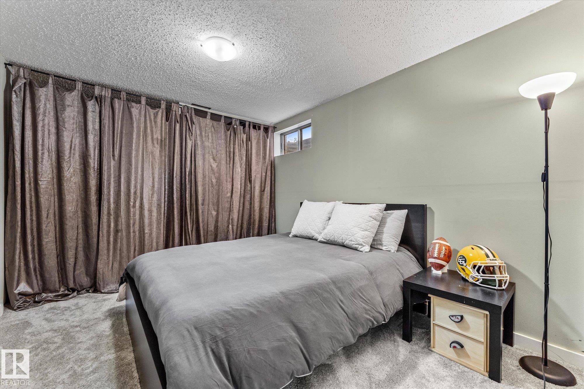 This room features soft gray wall paint, carpeting, and a window with a view of the outside - 3908 44 Avenue, Stony Plain, AB - Indoor Photo Showing Bedroom