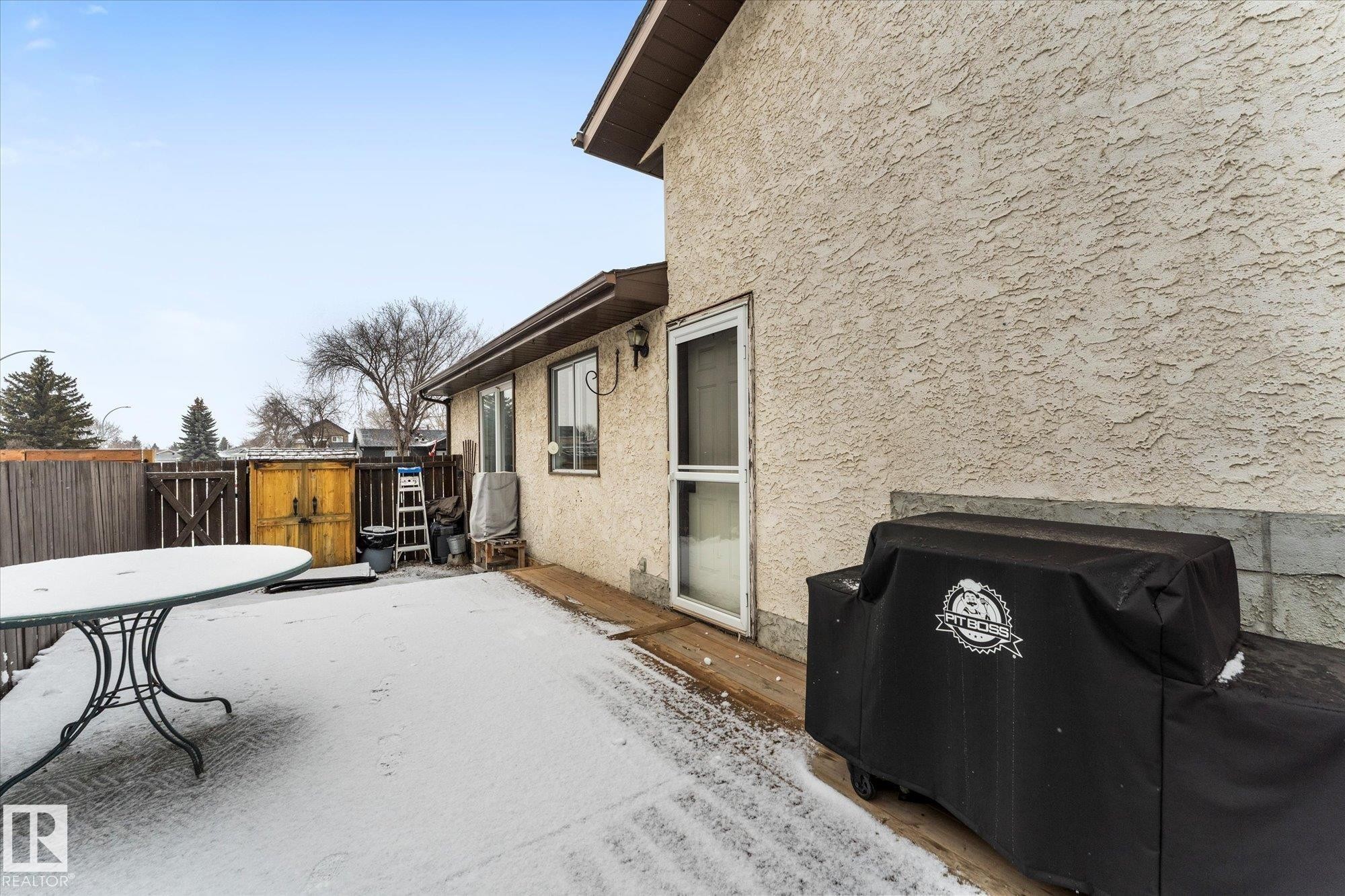 The property features an exterior entrance to a patio area with a wooden fence - 3908 44 Avenue, Stony Plain, AB - Outdoor