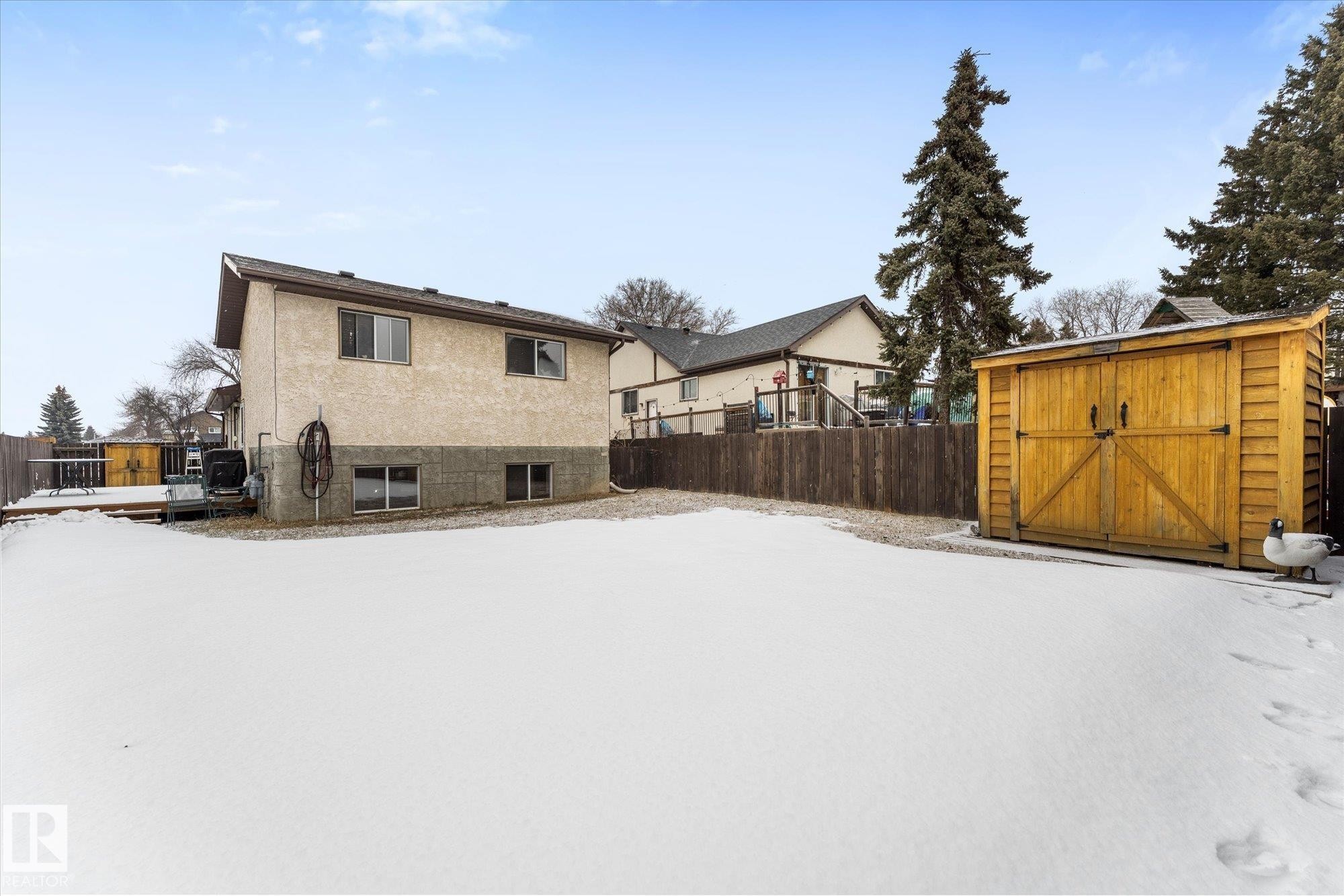 The property features a spacious backyard with a wooden storage shed and mature trees - 3908 44 Avenue, Stony Plain, AB - Outdoor