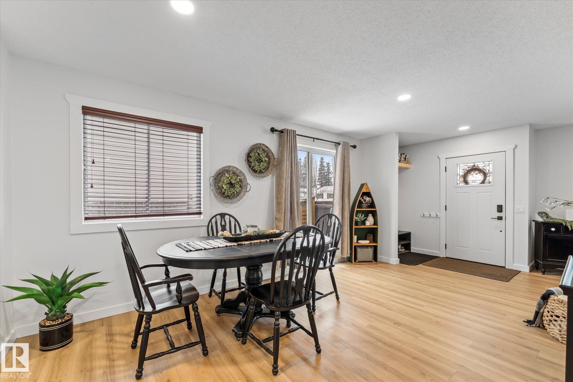 Well-lit dining area featuring light-colored hardwood flooring, a large window with blinds, and recessed lighting - 3908 44 Avenue, Stony Plain, AB - Indoor Photo Showing Dining Room