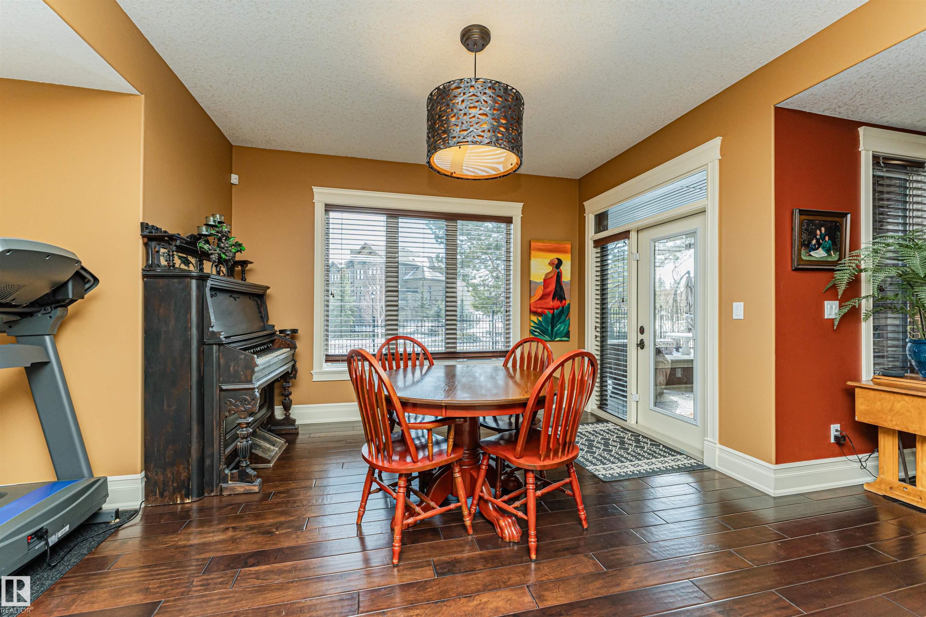 Living space featuring hardwood flooring, a dining area with a round table and chairs, and a glass-paneled door leading to the exterior - 3048 Watson Landing, Edmonton, AB - Indoor Photo Showing Dining Room