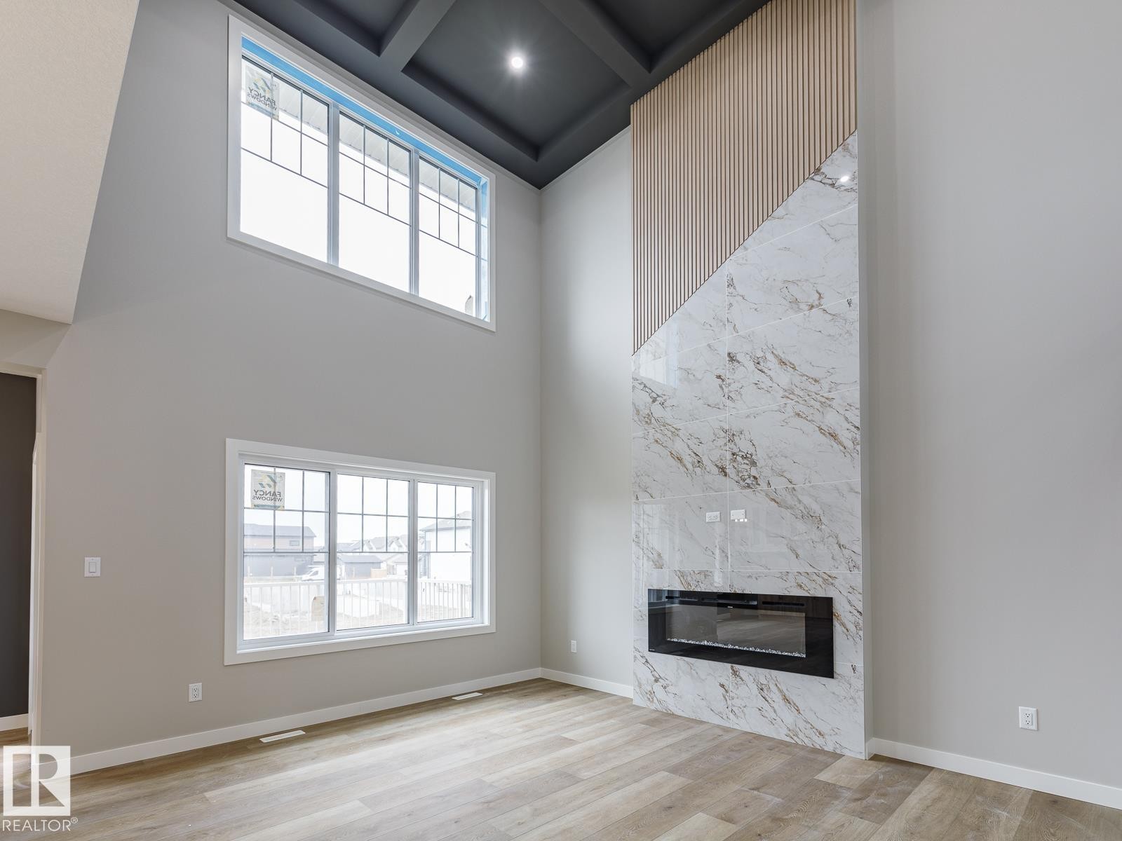 Two-story living area featuring a contemporary fireplace with a stone-finish facade and built-in electric insert - 917 Elderberry Landing, Edmonton, AB - Indoor Photo Showing Living Room With Fireplace