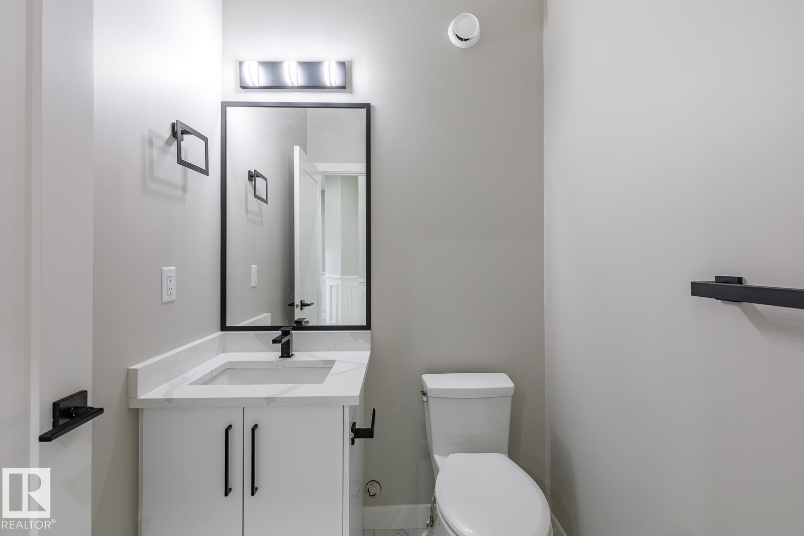 Bathroom featuring a modern vanity with a white countertop and integrated sink, matte black faucet, and a rectangular mirror with a black frame - 917 Elderberry Landing, Edmonton, AB - Indoor Photo Showing Bathroom