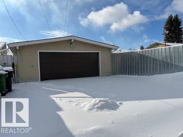 Detached garage featuring a brown garage door and a light-colored stucco exterior - 11003 144 Street, Edmonton, AB - Outdoor