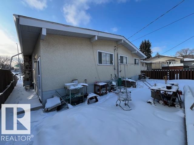 The property features a neutral stucco exterior, a fenced yard, and a stone accent wall - 11003 144 Street, Edmonton, AB - Outdoor With Exterior