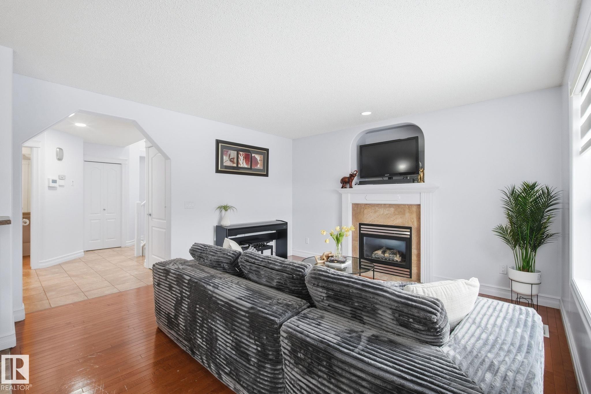 Living area featuring a fireplace with a stone surround and a white mantel - 3016 24 Ave, Edmonton, AB - Indoor Photo Showing Living Room With Fireplace