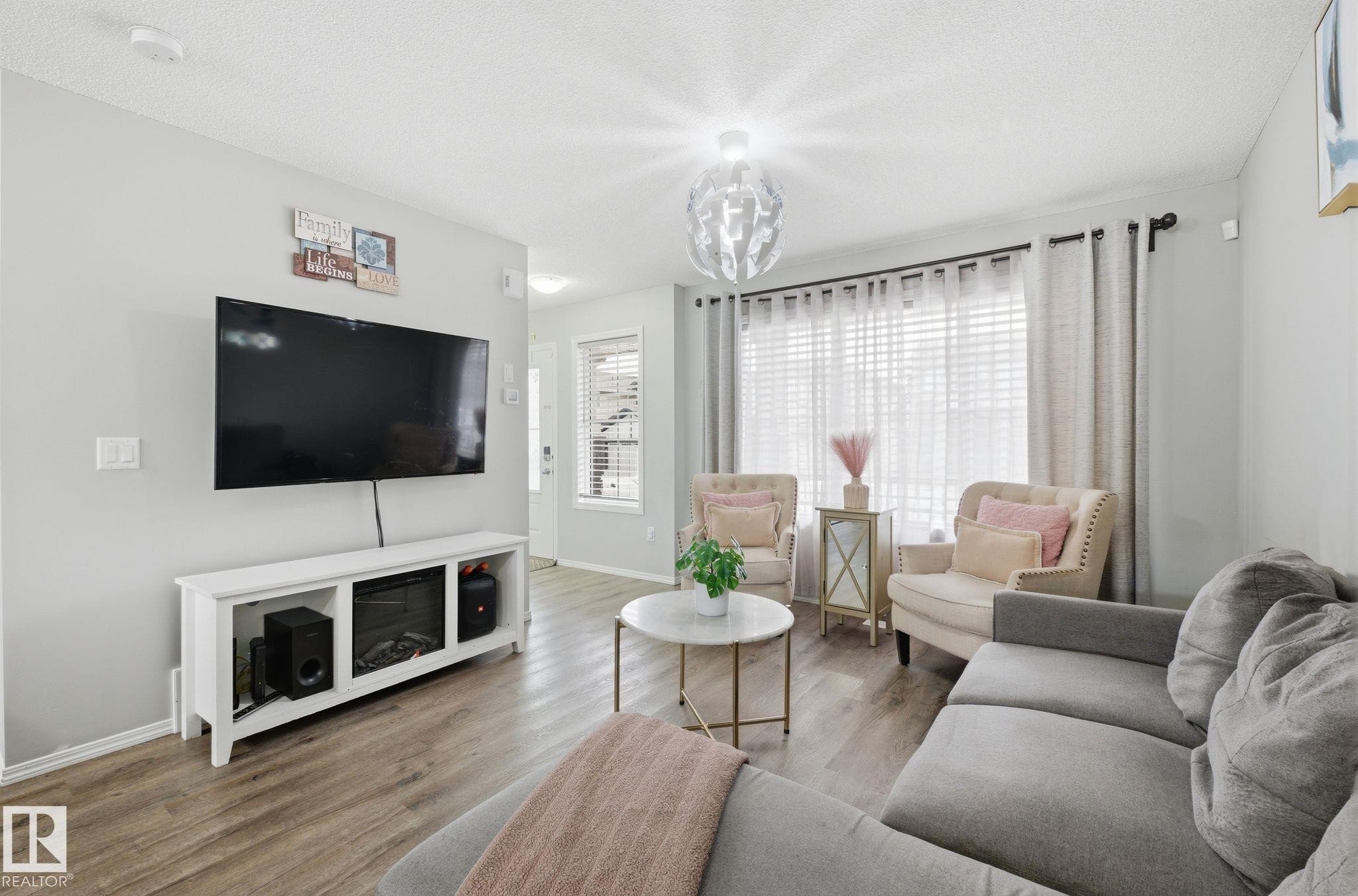 This living area features light-colored walls and wood-look flooring - 4636 175 Ave, Edmonton, AB - Indoor Photo Showing Living Room