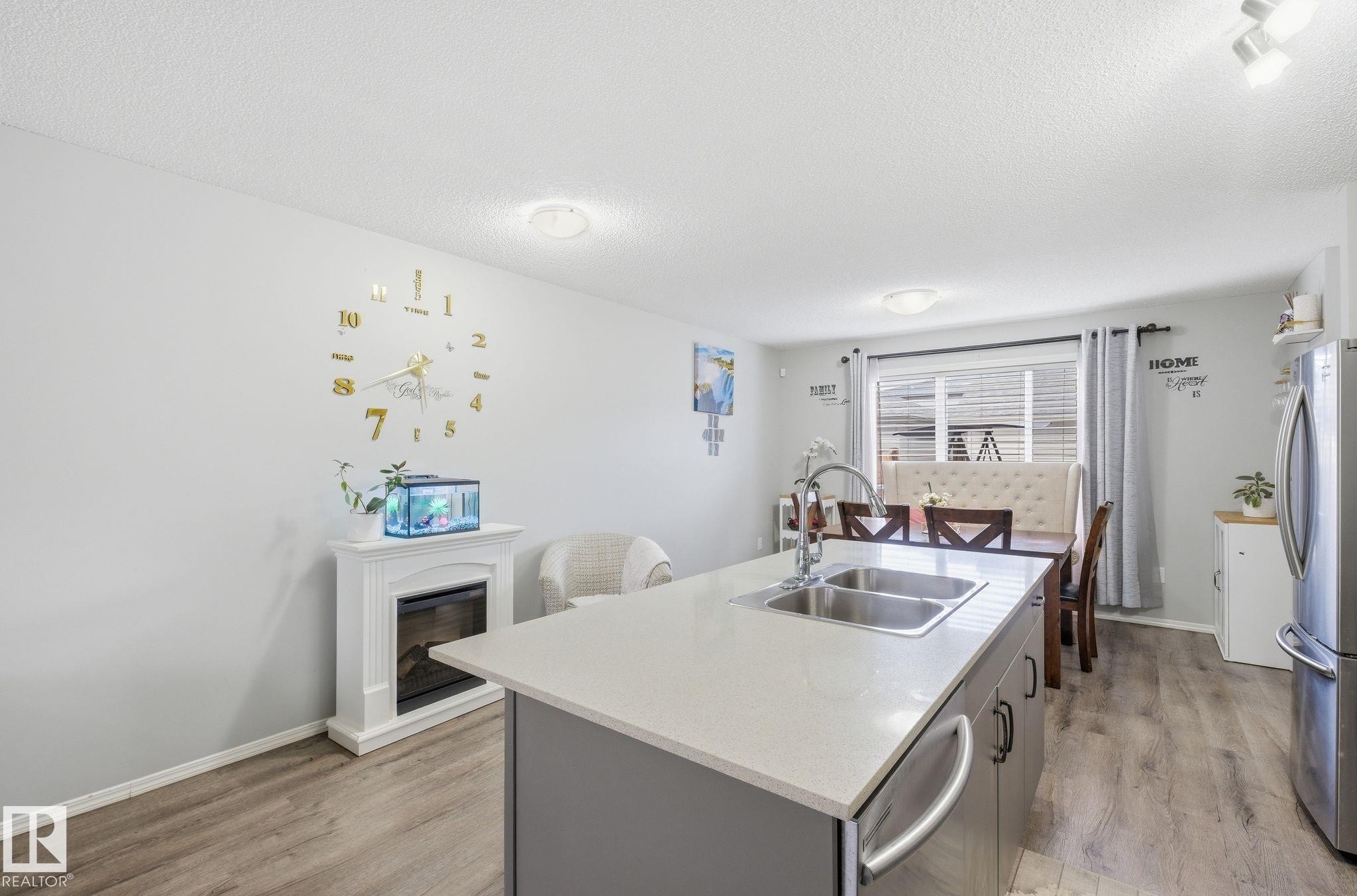 The property features an open-concept living area with light-colored walls and wood-look flooring - 4636 175 Ave, Edmonton, AB - Indoor Photo Showing Kitchen With Double Sink