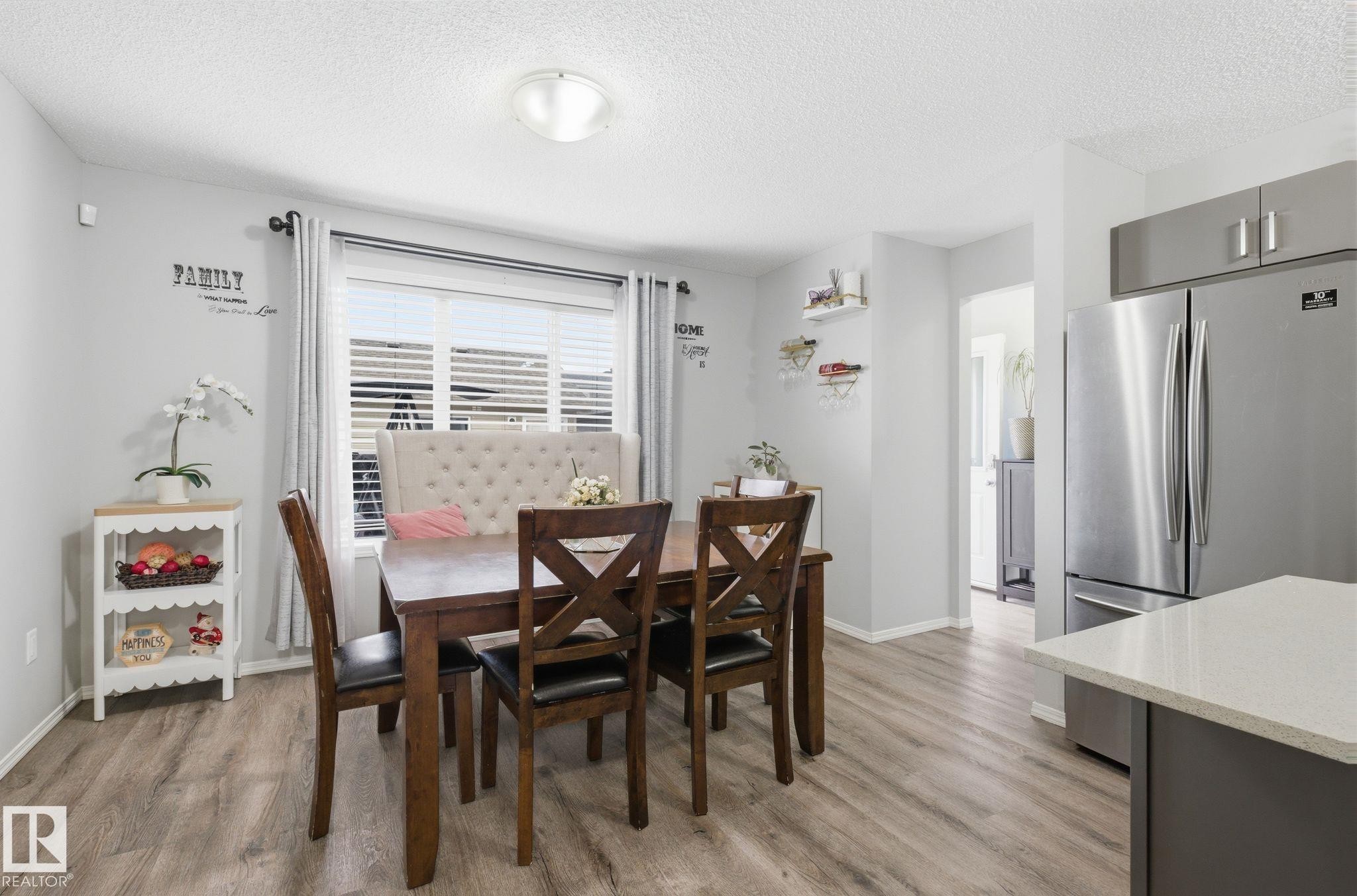 This dining area features wood-look flooring and a window with blinds, providing natural light - 4636 175 Ave, Edmonton, AB - Indoor Photo Showing Dining Room
