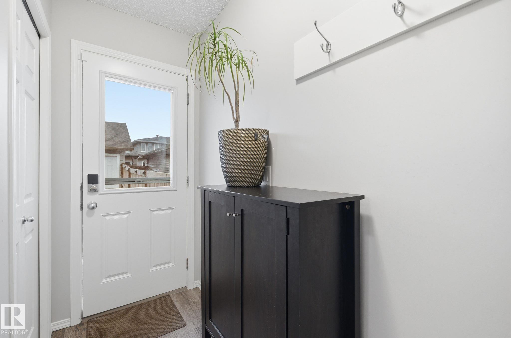 Entryway featuring a white door with a window, light-colored walls, and a coat rack with hooks - 4636 175 Ave, Edmonton, AB - Indoor Photo Showing Other Room