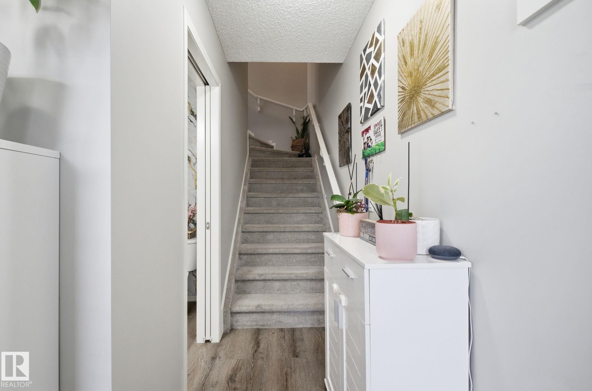 Inviting entry area with light grey walls, carpeted stairs, and wood-style flooring - 4636 175 Ave, Edmonton, AB - Indoor Photo Showing Other Room