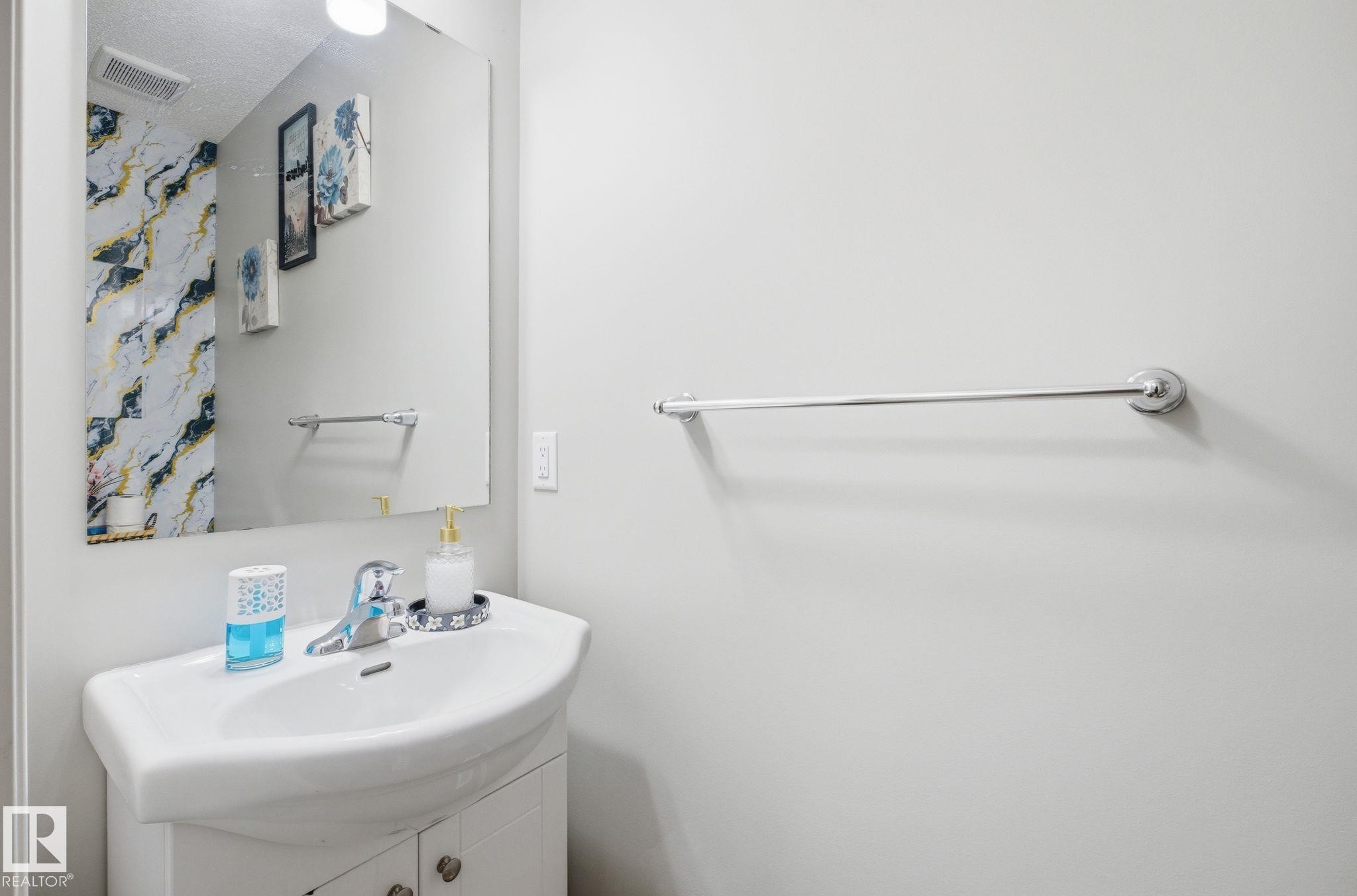 Bathroom featuring a white vanity with a ceramic sink and a chrome faucet, set against light-colored walls - 4636 175 Ave, Edmonton, AB - Indoor Photo Showing Bathroom