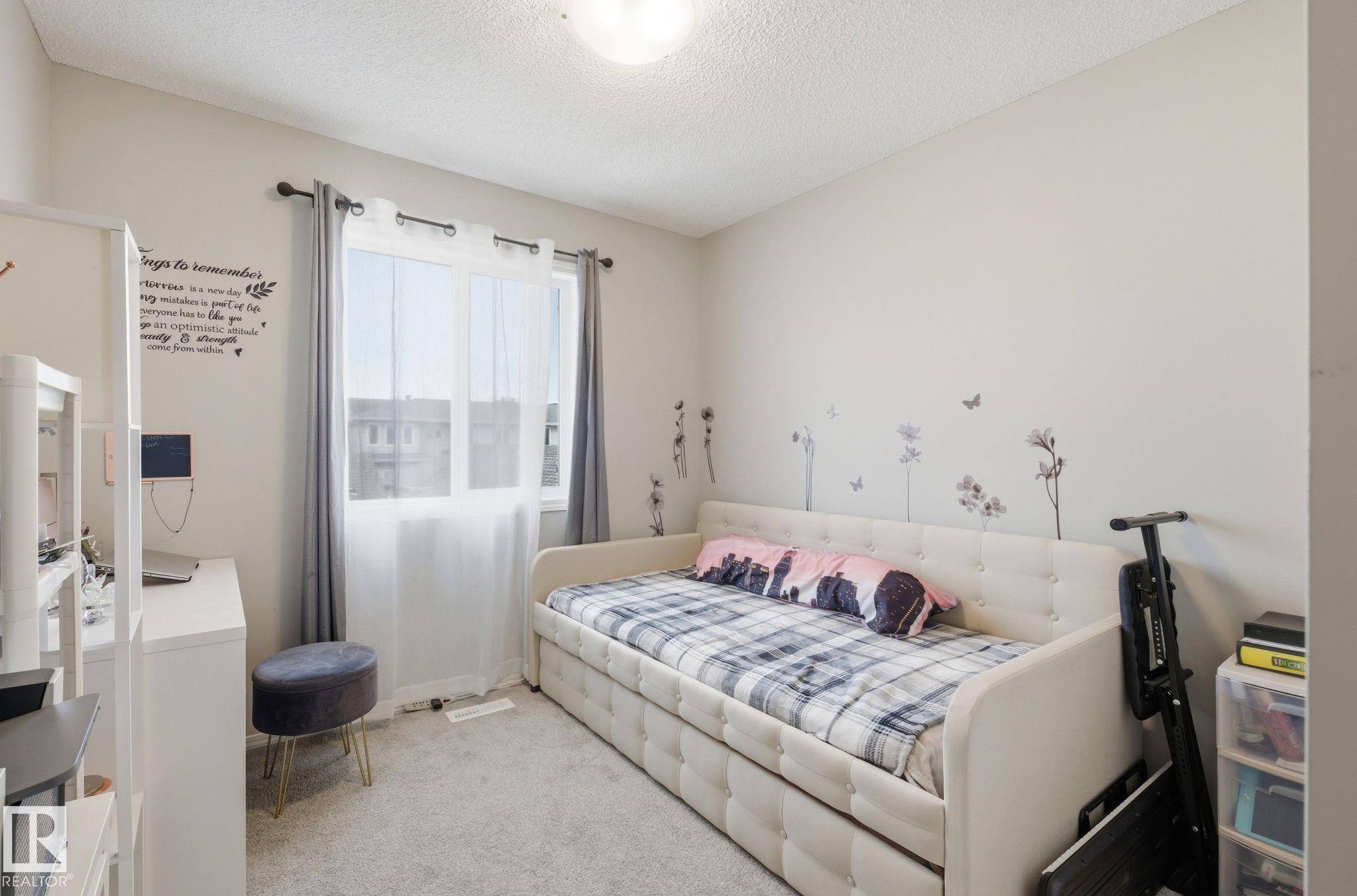 This bright room features a window with sheer and blackout curtains, light-colored walls, and carpeting - 4636 175 Ave, Edmonton, AB - Indoor Photo Showing Bedroom