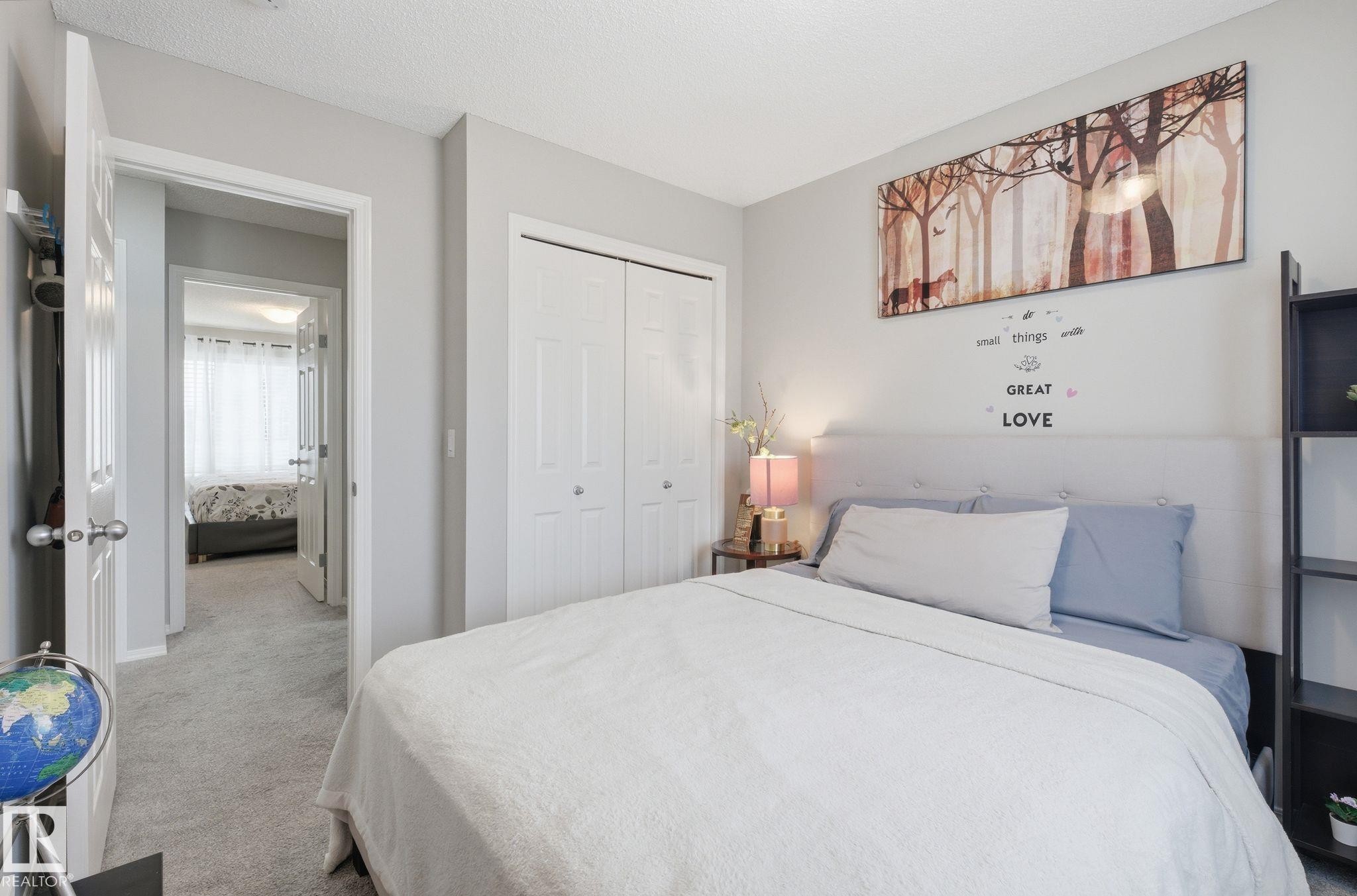 The bedroom features light gray walls, light gray carpet, and white bi-fold closet doors - 4636 175 Ave, Edmonton, AB - Indoor Photo Showing Bedroom