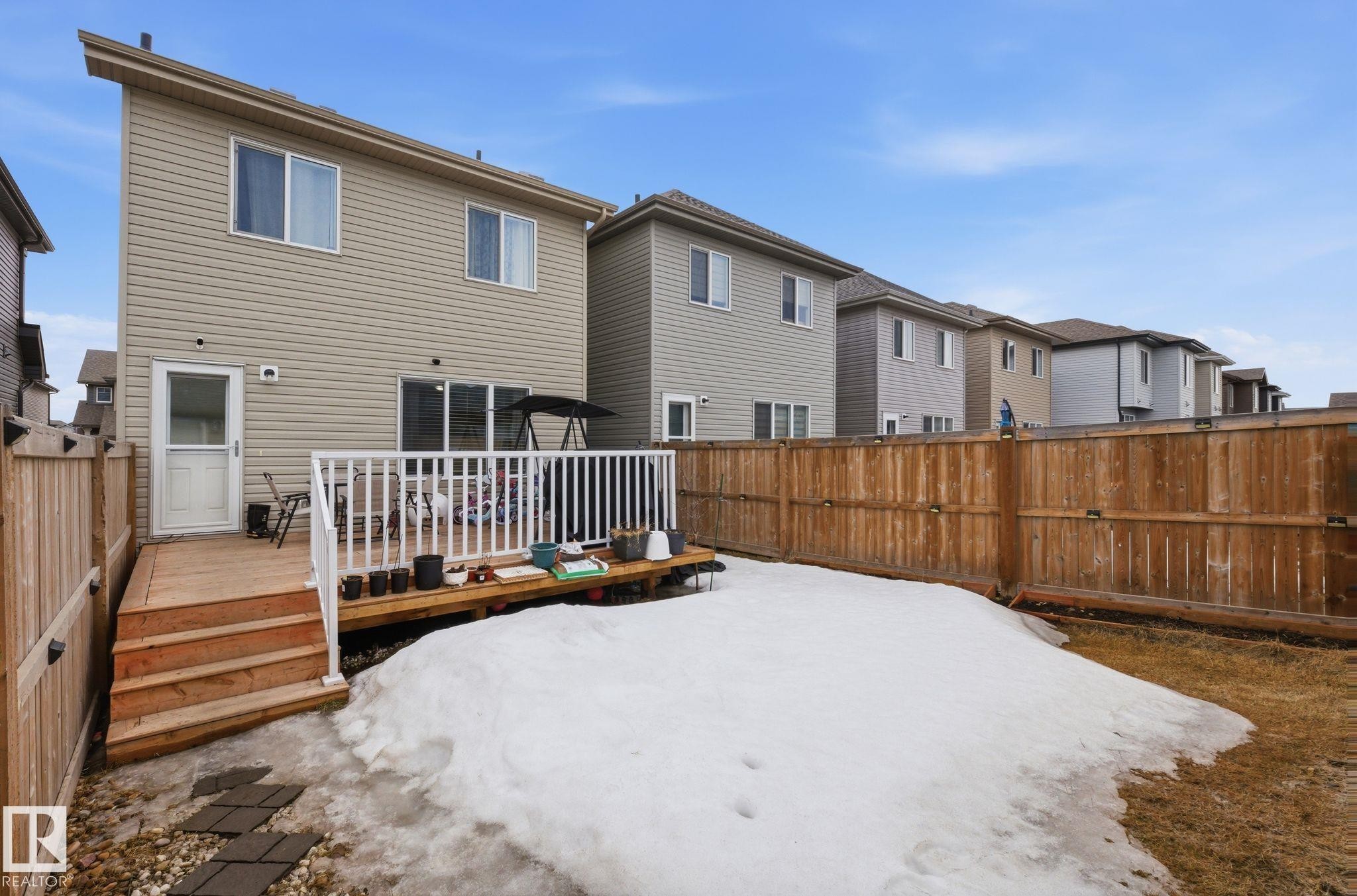 The property features a wooden deck with white railings, accessible via a glass-paneled door and a sliding glass door - 4636 175 Ave, Edmonton, AB - Outdoor With Exterior