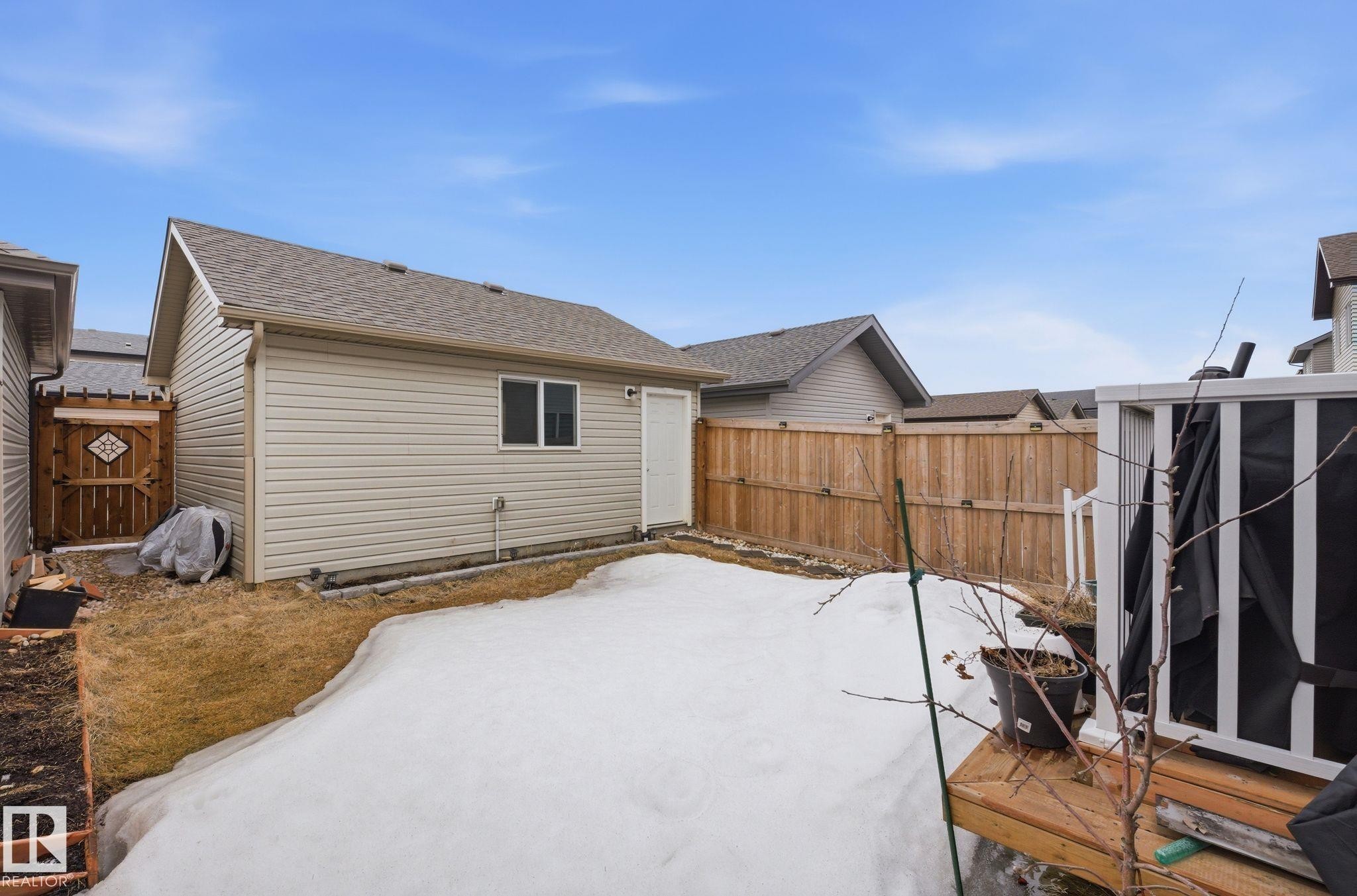 The property features a detached building with light-colored siding and a shingled roof, a wooden fence enclosing a portion of the yard, and a wooden gate - 4636 175 Ave, Edmonton, AB - Outdoor With Exterior