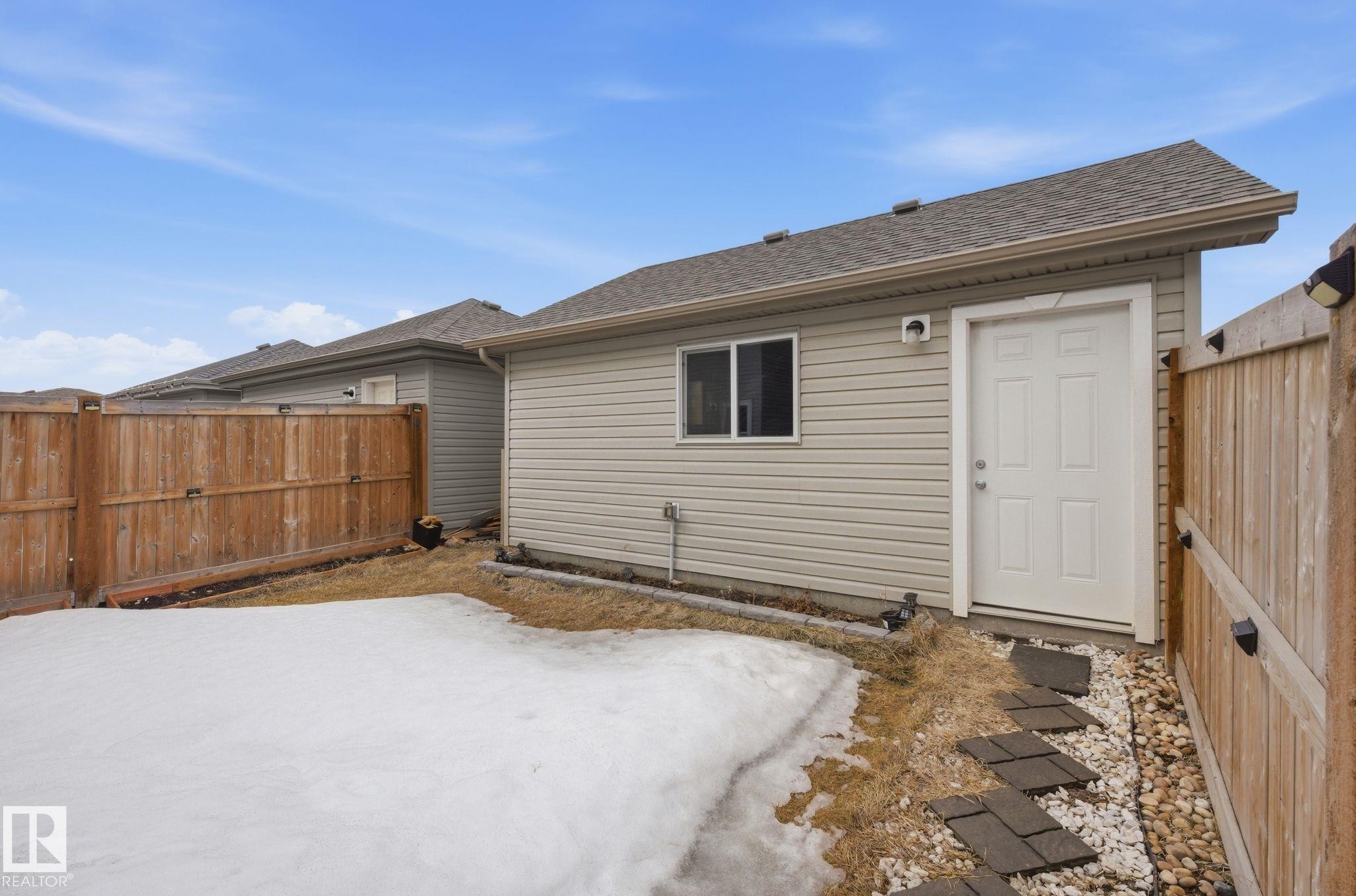 The property features a fenced yard with a gate, a storage shed with a window, and a pathway composed of stepping stones and decorative rocks - 4636 175 Ave, Edmonton, AB - Outdoor With Exterior