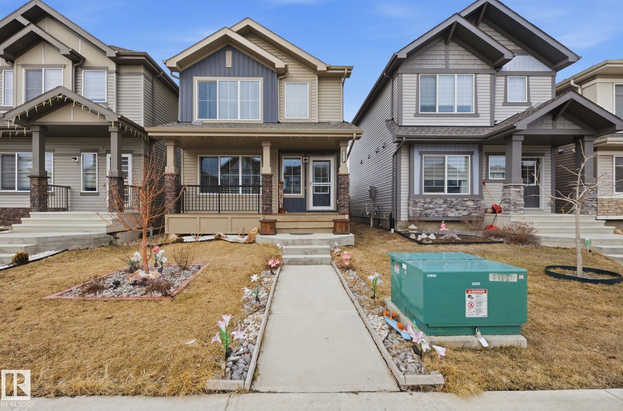 The property features a two-story exterior with a porch, a front walkway, and a small landscaped area with rocks and decorative flowers - 4636 175 Ave, Edmonton, AB - Outdoor With Facade