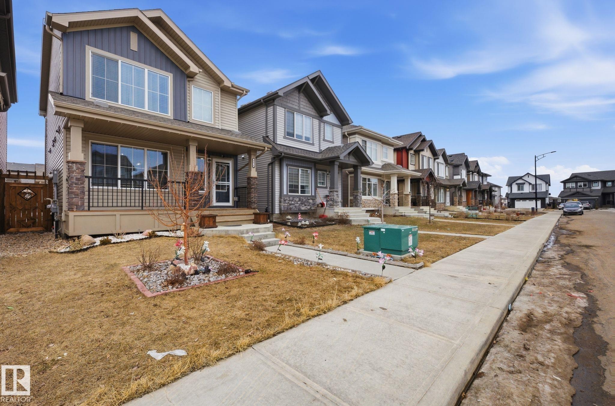 The property features a front porch with dark railings and stone accents, complemented by a front yard with a landscaped garden bed - 4636 175 Ave, Edmonton, AB - Outdoor
