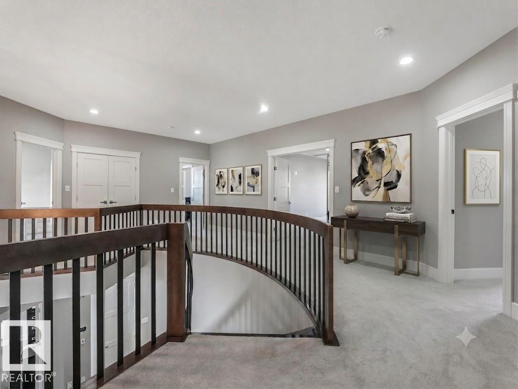 Upper-level landing featuring a curved staircase with dark wood handrails and black balusters - 8927 120 Street Nw, Edmonton, AB - Indoor Photo Showing Other Room