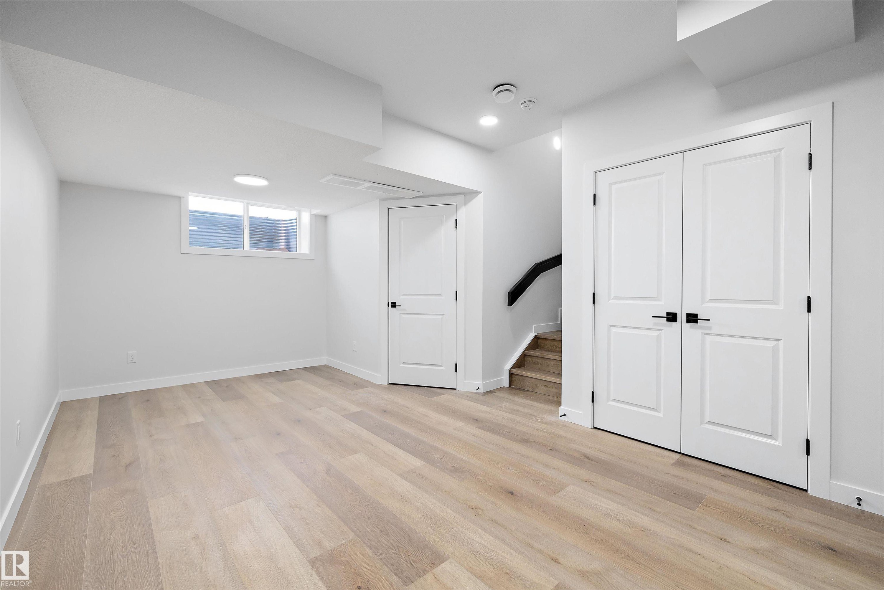 Spacious room featuring light wood-finish flooring, white walls, and a large egress window - 954 Elderberry Landing, Edmonton, AB - Indoor Photo Showing Other Room