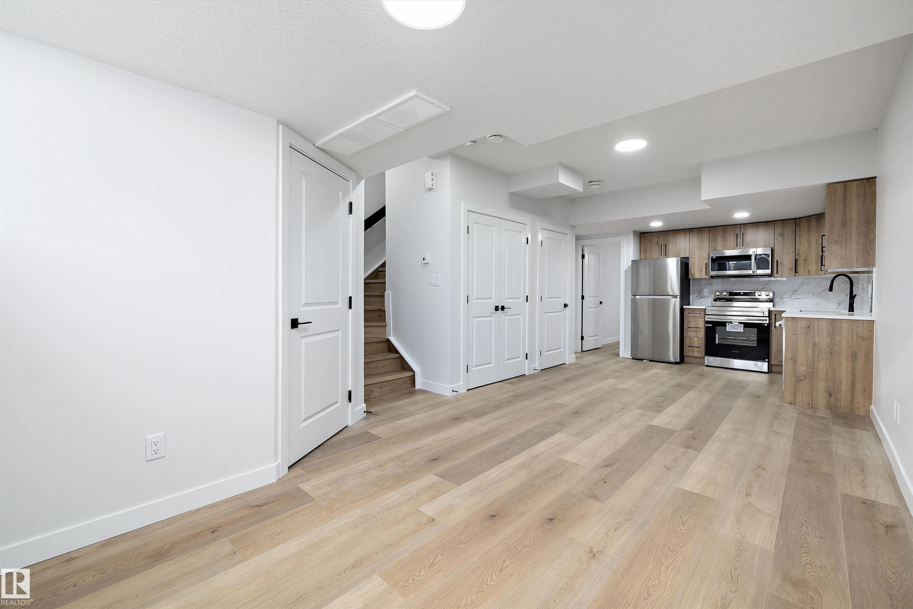 Open-concept living space featuring wood-finish flooring, recessed lighting, and a modern kitchen with stainless steel appliances - 954 Elderberry Landing, Edmonton, AB - Indoor Photo Showing Kitchen