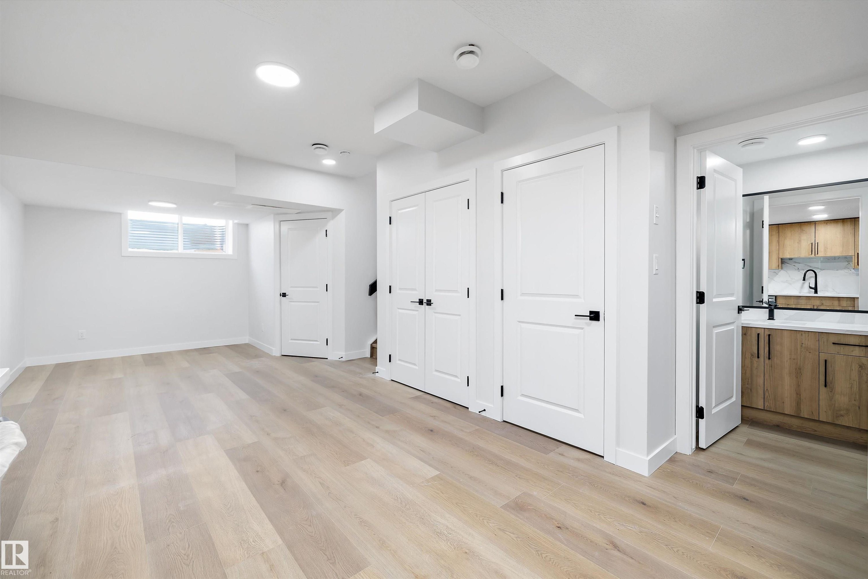 Bright lower-level room featuring light wood-finish flooring, recessed lighting, and a window - 954 Elderberry Landing, Edmonton, AB - Indoor
