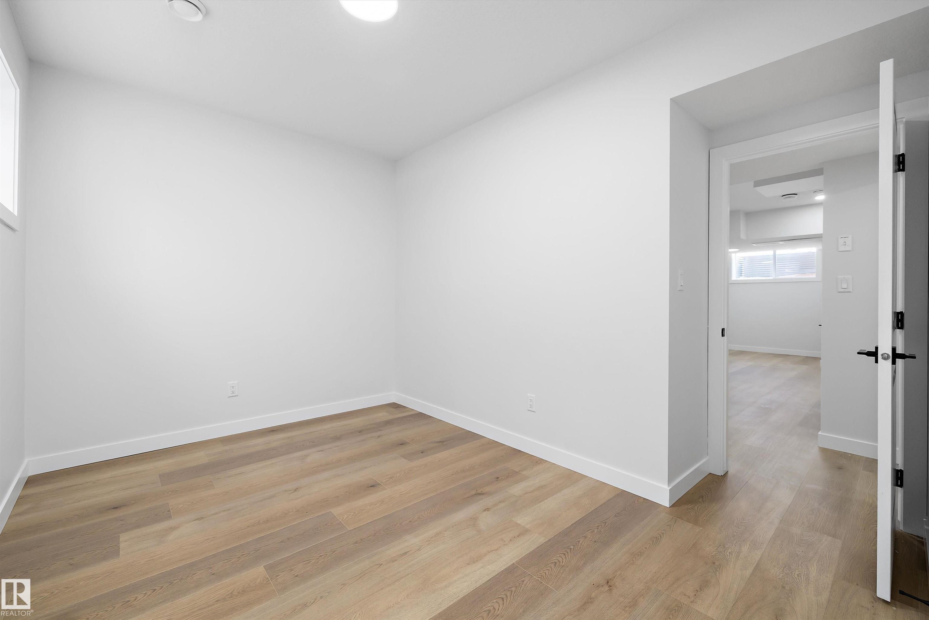 Bright interior space featuring light wood-finish flooring, white baseboards, and a white door with black hardware - 954 Elderberry Landing, Edmonton, AB - Indoor Photo Showing Other Room